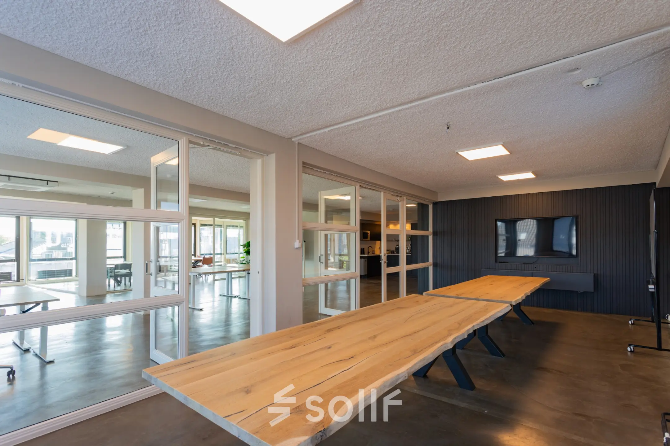 Moderne kantoorruimte te huur op Kleine Gartmanplantsoen 21, Amsterdam Centrum, met houten tafels en glazen wanden. Deze kantoorpand biedt een slimme werkruimte in het bruisende hart van de stad.
