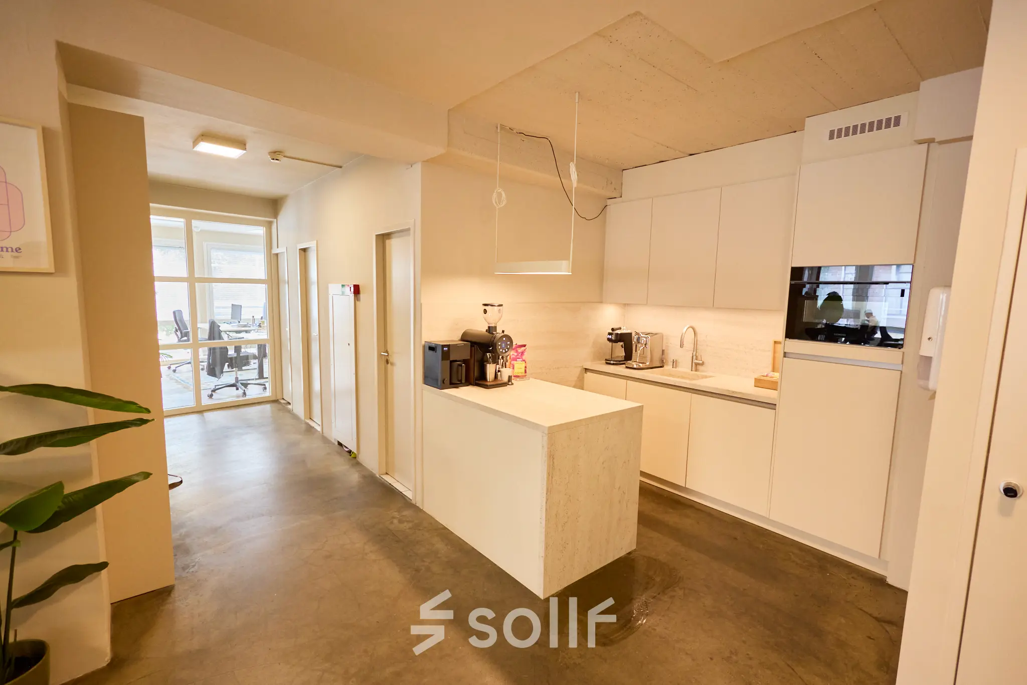 Moderne kitchenette in kantoorpand op Kleine Gartmanplantsoen 21, Amsterdam Centrum, met strakke witte kasten en apparatuur tegen een betonnen vloer en plafond. Kantoorruimte huren in een levendig gedeelte van Amsterdam.