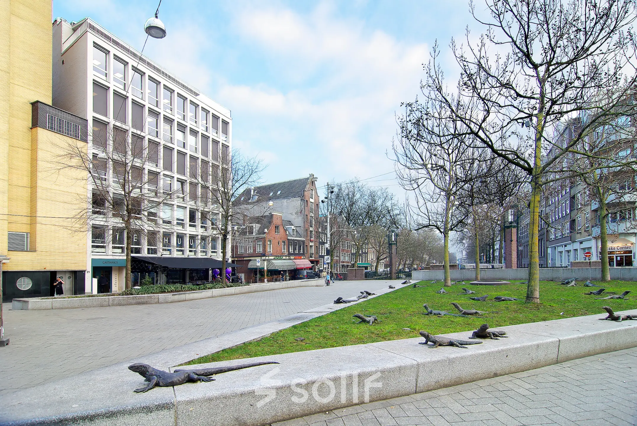Buitenzijde van kantoorpand op Kleine Gartmanplantsoen 21 in Amsterdam Centrum, omringd door bomen en straatkunst. Mogelijkheid voor kantoorruimte huren in de drukke binnenstad.