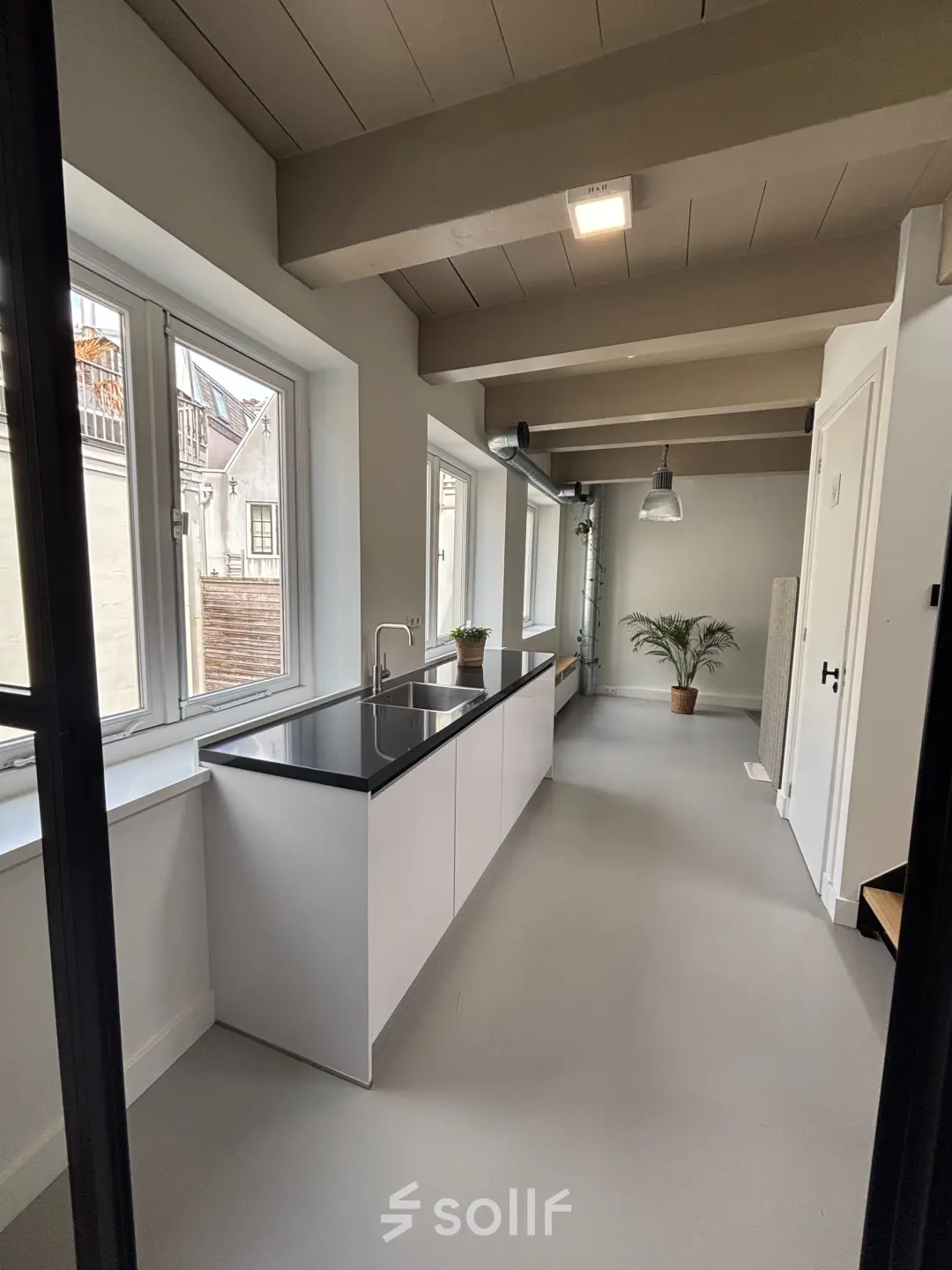 Lichte kantoorruimte te huur aan de Kloveniersburgwal 131K in Amsterdam Centrum, met moderne keuken en grote ramen. Het interieur is strak en uitnodigend.