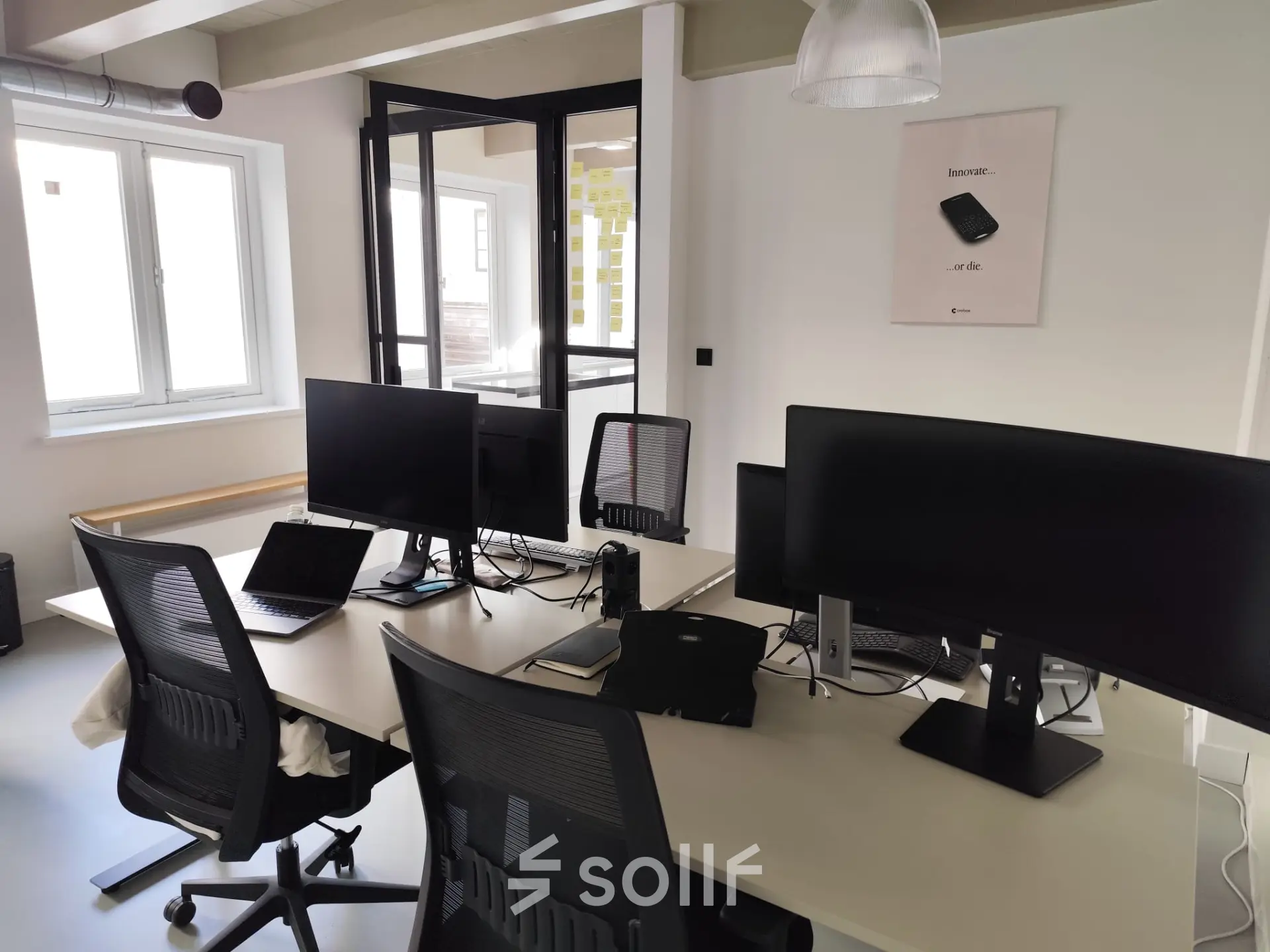 Moderne kantoorruimte in Amsterdam Centrum met werkplekken, bureaus en computerschermen op Kloveniersburgwal 131K, ideaal voor kantoorruimte huren in stijlvol kantoorpand.