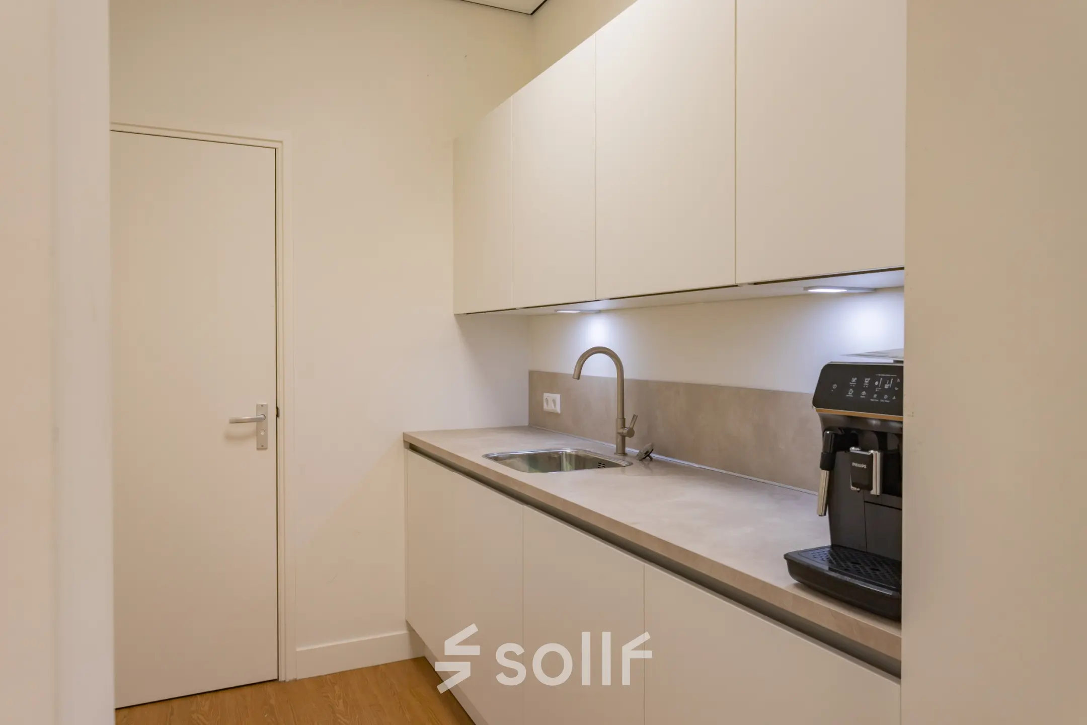 Moderne pantry in kantoorpand op Korte Leidsedwarsstraat 133A, Amsterdam Centrum, met witte kasten en espressomachine, ideaal voor huur in deze kantoorruimte.