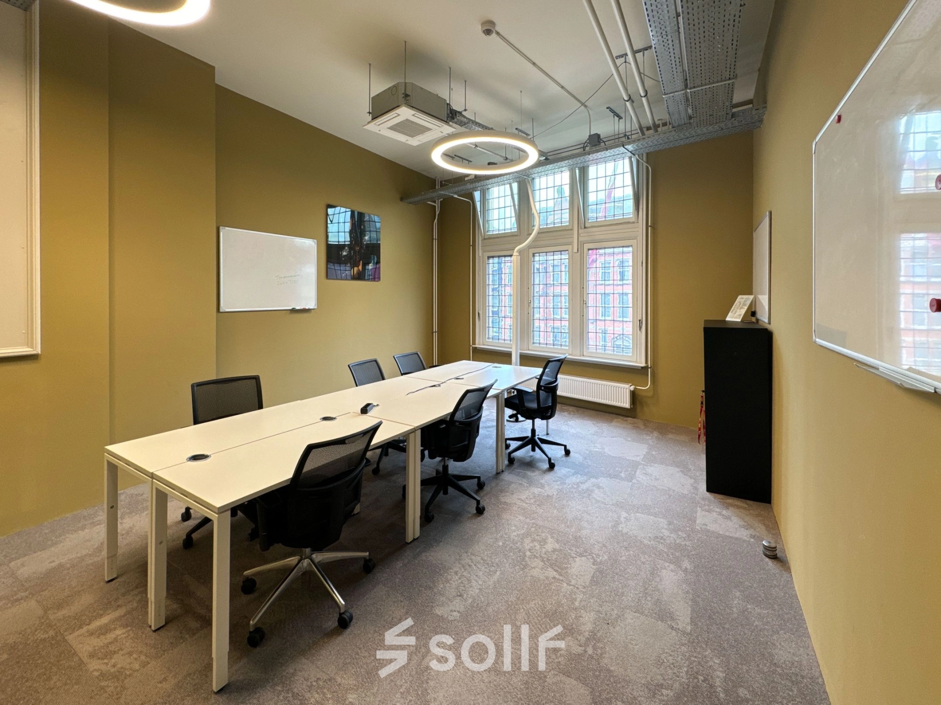 Kantoorruimte huren op Nieuwezijds Voorburgwal 104-108 in Amsterdam Centrum, met een vergadertafel, stoelen, en een whiteboard.