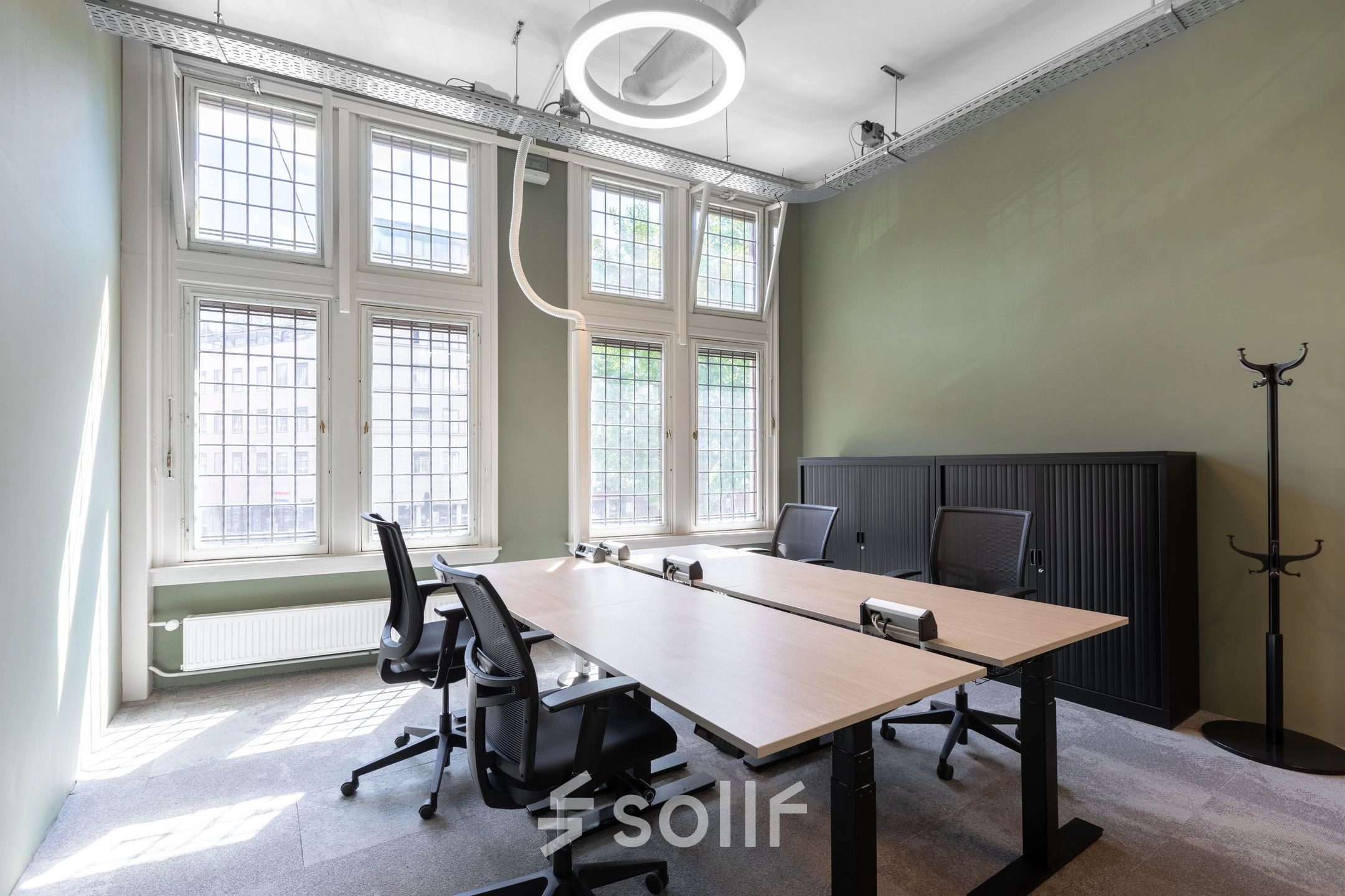 Interieur van een moderne kantoorruimte te huur op Nieuwezijds Voorburgwal 104-108 in Amsterdam Centrum, met grote ramen, bureaus en stoelen.