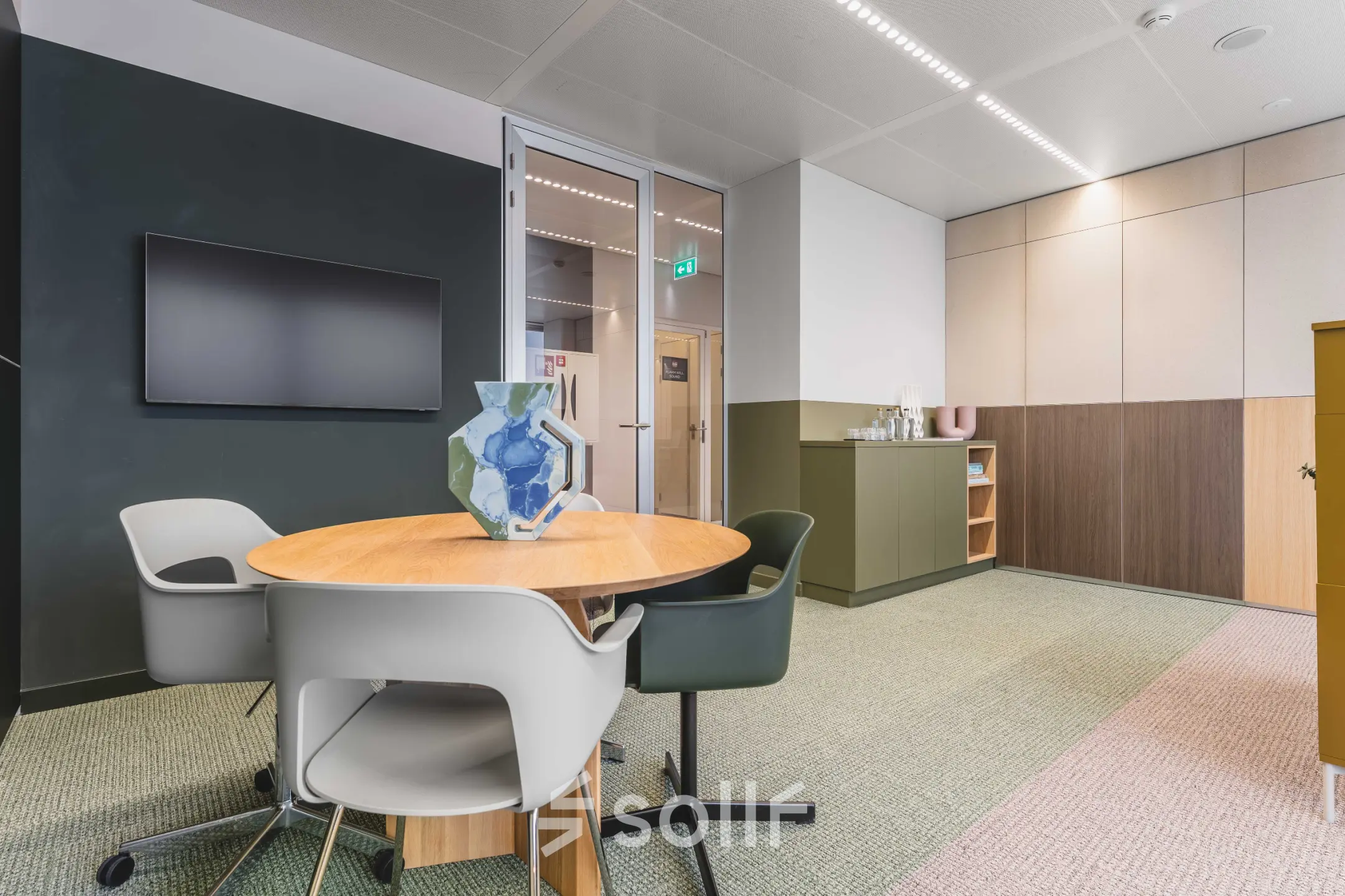 Kantoorruimte huren in modern kantoorpand aan de Piet Heinkade 55, Amsterdam Centrum. Stijlvolle vergadertafel met stoelen, geschikt voor zakelijke bijeenkomsten. Neutrale kleuren en glazen deuren creëren een lichte en open sfeer.