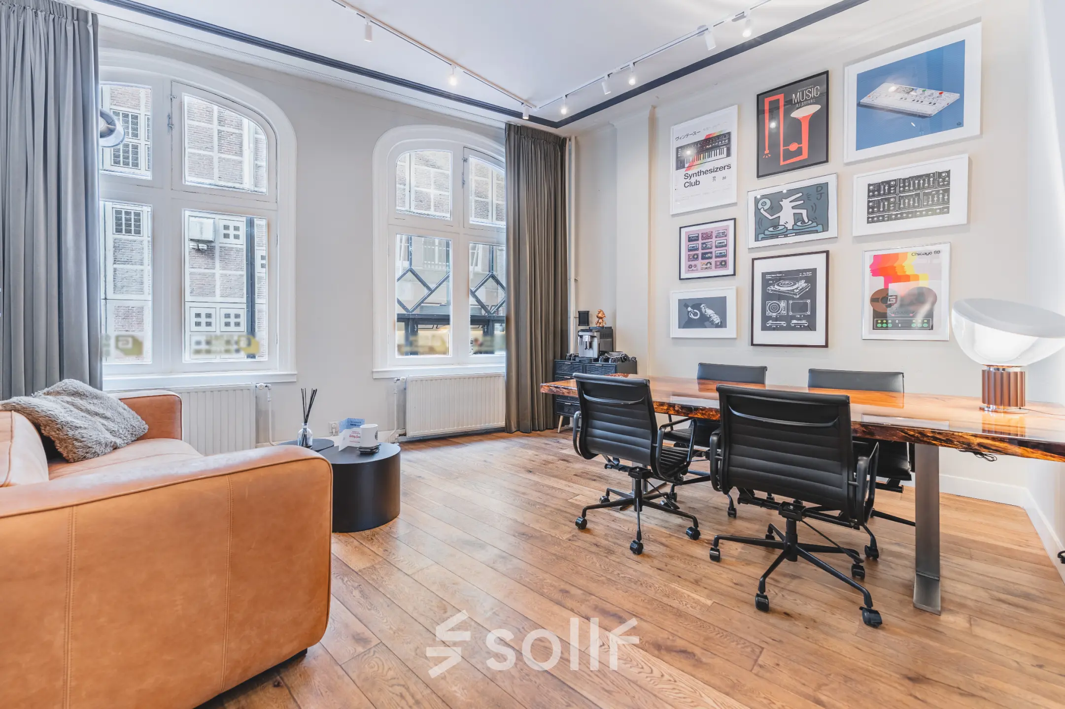 Moderne kantoorruimte huren aan de Warmoesstraat 149 - 151 in Amsterdam Centrum met grote ramen, houten vloeren en een vergadertafel met stoelen.