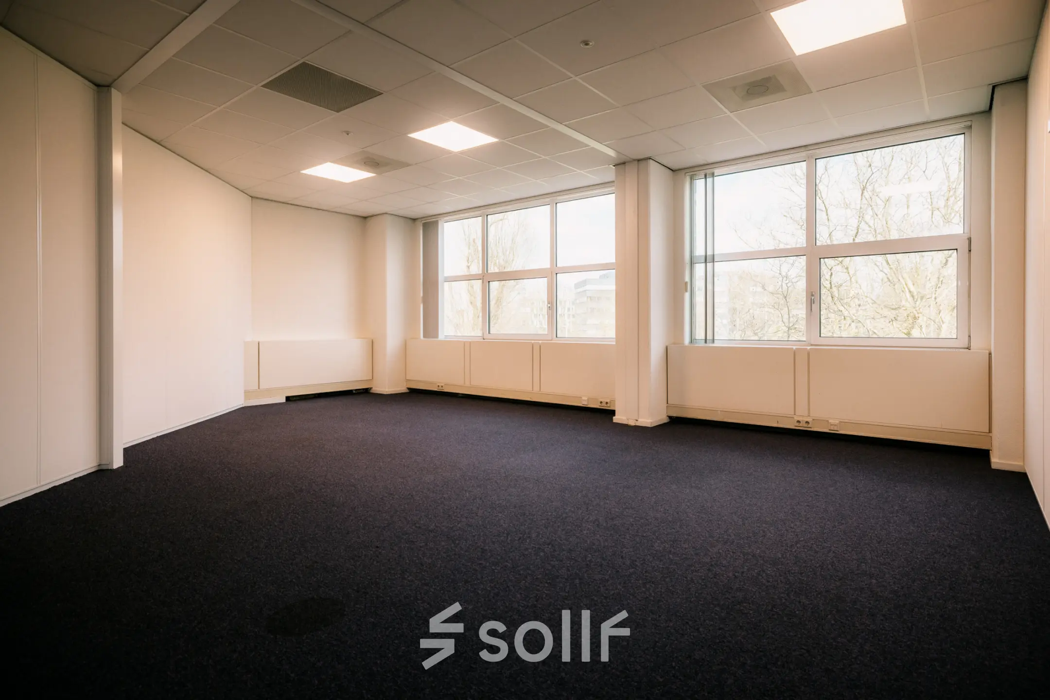 Ruime kantoorkamer op Overschiestraat 182, Amsterdam De Schinkel voor kantoorruimte huren. Grote ramen zorgen voor natuurlijk licht op de blauwe vloeren, ideaal voor een flexibel indeelbare werkruimte.