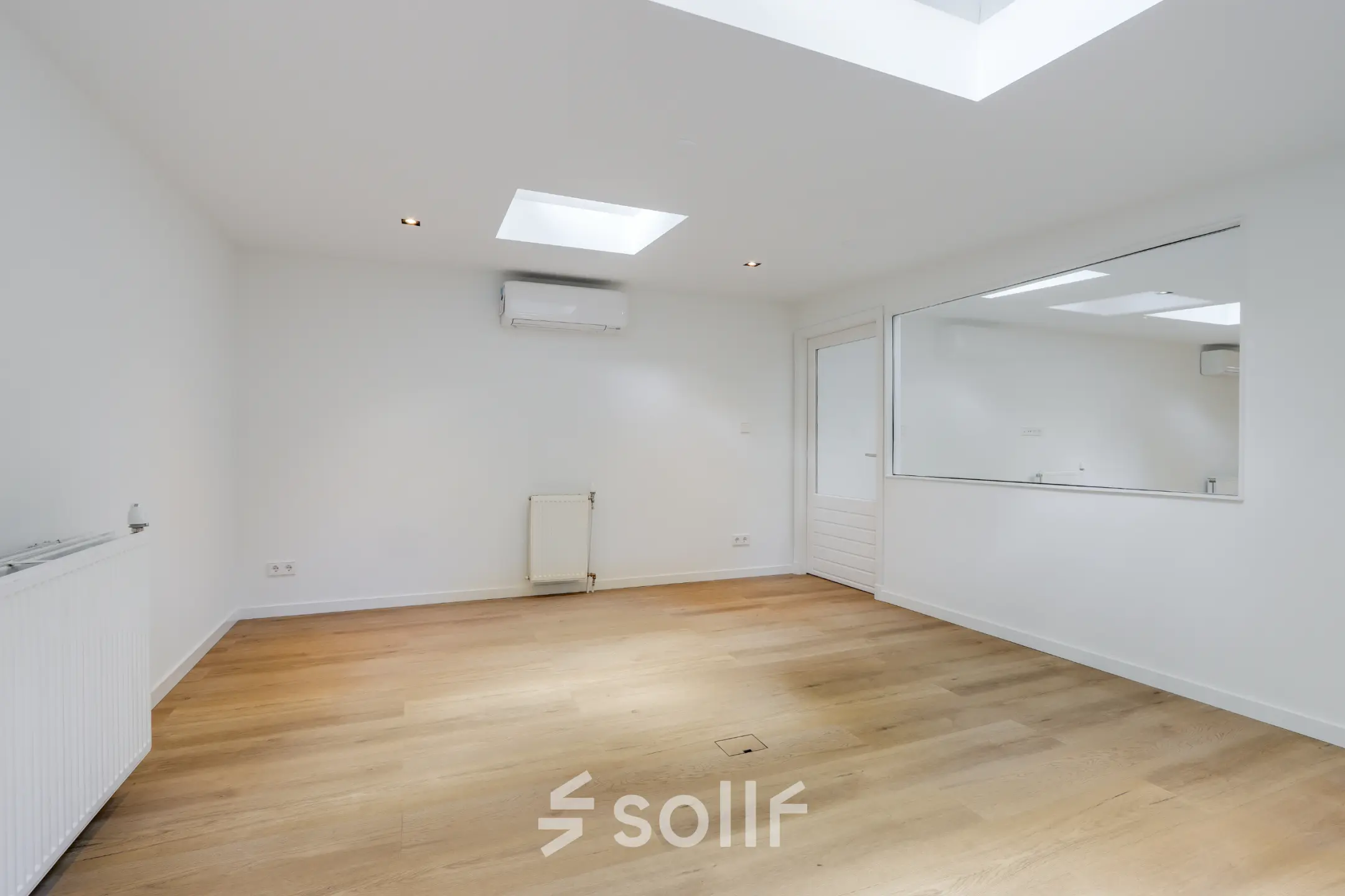 Lichte kantoorruimte met houten vloer en wit geverfde wanden op Schinkelkade 44, Amsterdam De Schinkel. Voorzien van luchtvering en groot raam.