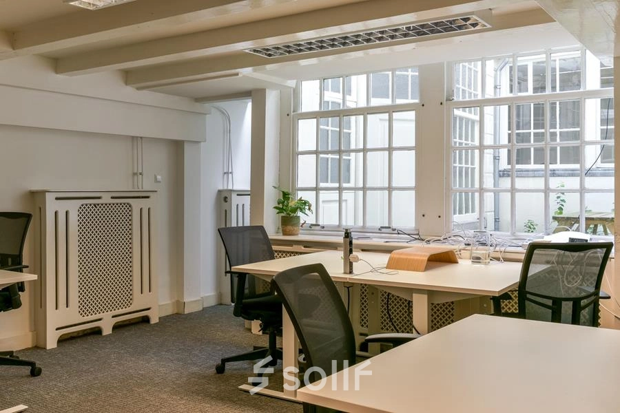 Kantoor aan de Herengracht 338 in Amsterdam Grachtengordel met moderne bureaus en stoelen in een lichte ruimte, geschikt voor kantoorruimte huren. Grote ramen zorgen voor veel natuurlijk licht.