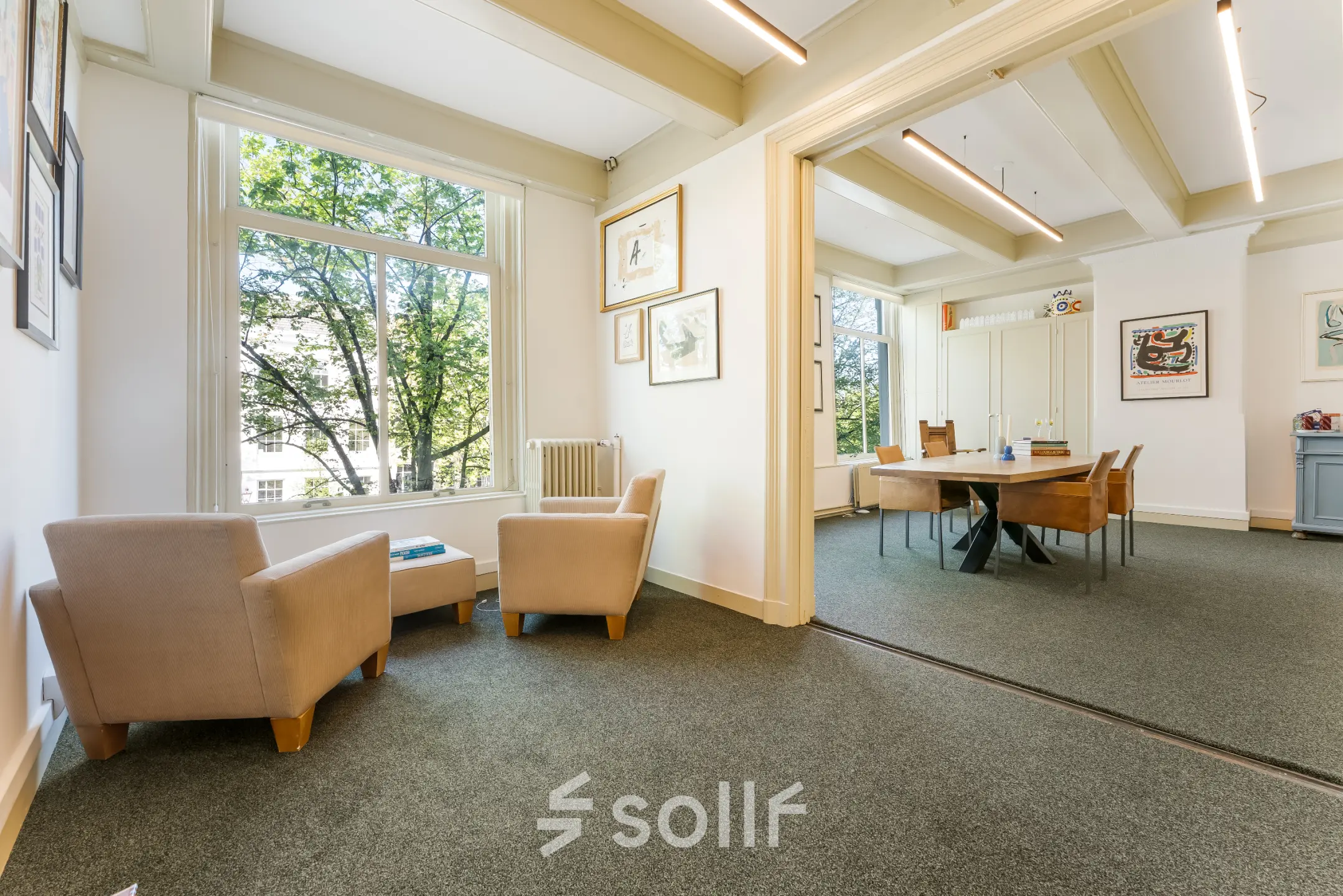 Kantoorruimte huren met uitzicht op de Amsterdamse gracht, helder interieur met comfortabele zitplaatsen en vergadertafel.