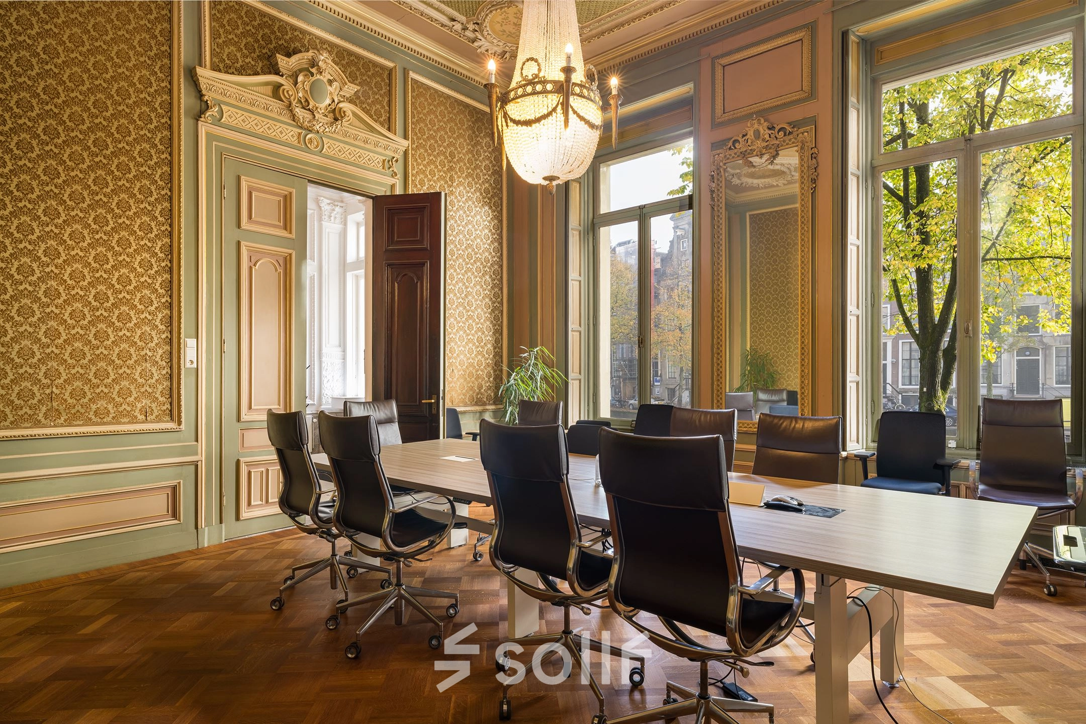 Kantoorruimte huren aan de Keizersgracht 452 in Amsterdam Grachtengordel met klassieke inrichting en chique vergadertafel met zwarte stoelen, omringd door elegante houtpanelen en grote ramen.
