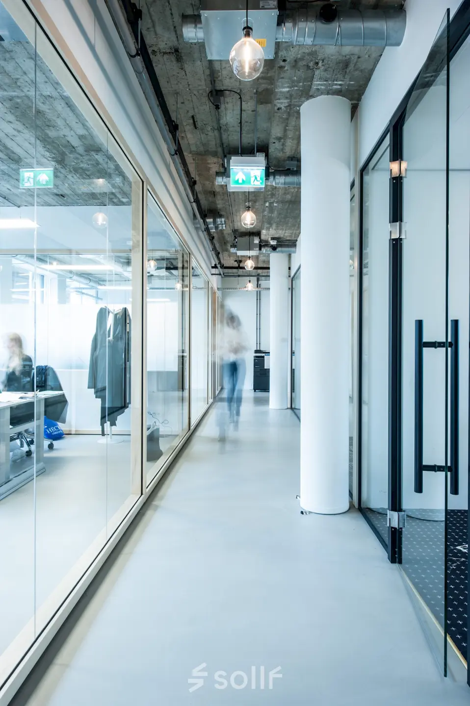 Modern kantoorpand op Singel 542 in Amsterdam Grachtengordel, met glazen wanden en zichtbare industriële elementen. Personen werken aan bureaus in een lichte ruimte.