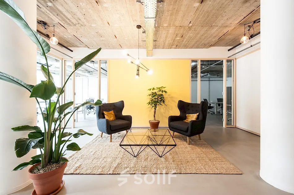 Moderne kantoorruimte met comfortabele stoelen en glazen tafel, omgeven door planten, te huur op Singel 542 in de Amsterdam Grachtengordel.