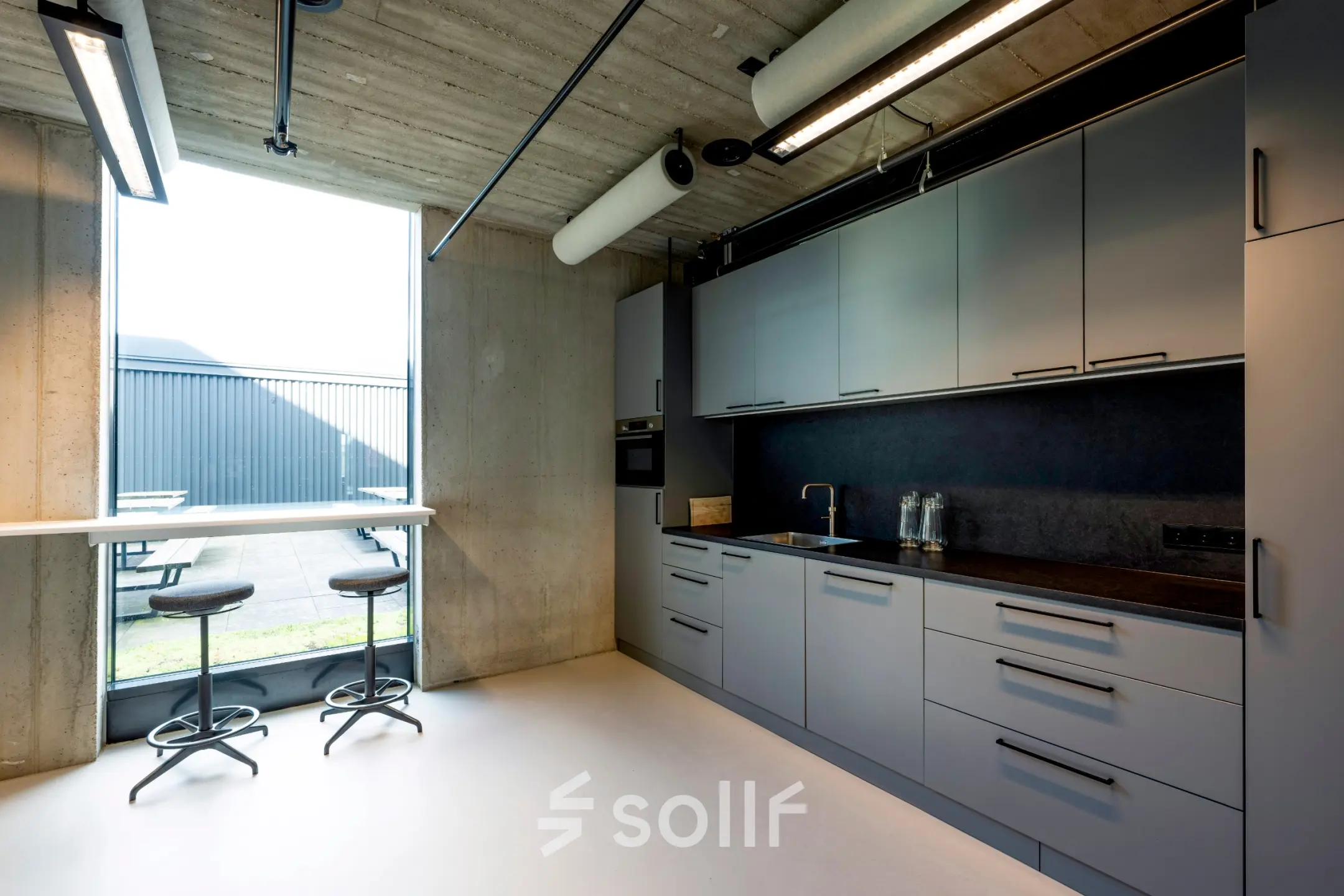 Moderne pantry in kantoorpand aan de Moermanskkade 109-113, Amsterdam Houthavens, met veel opbergruimte, strakke keukenapparatuur en uitzicht op een buitenzitje. Ideaal voor een kantoorruimte huren.