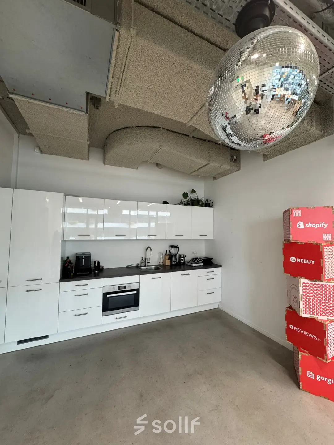 Een kantoorpand op Moermanskkade 303 in Amsterdam Houthavens met een eenvoudige keuken voorzien van een glimmende discobal en stapels dozen. Ideaal voor kantoorruimte huren.