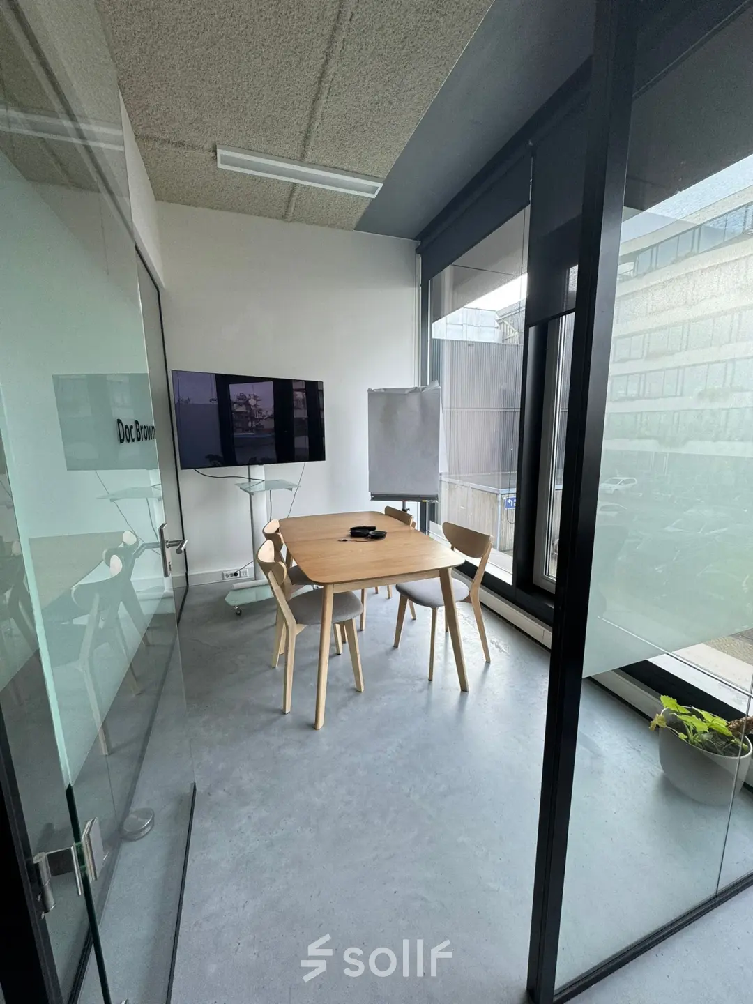 Kantoorruimte huren in Amsterdam Houthavens aan de Moermanskkade 303, met glazen wanden, houten tafel en stoelen, en een scherm, ideaal voor vergaderingen.
