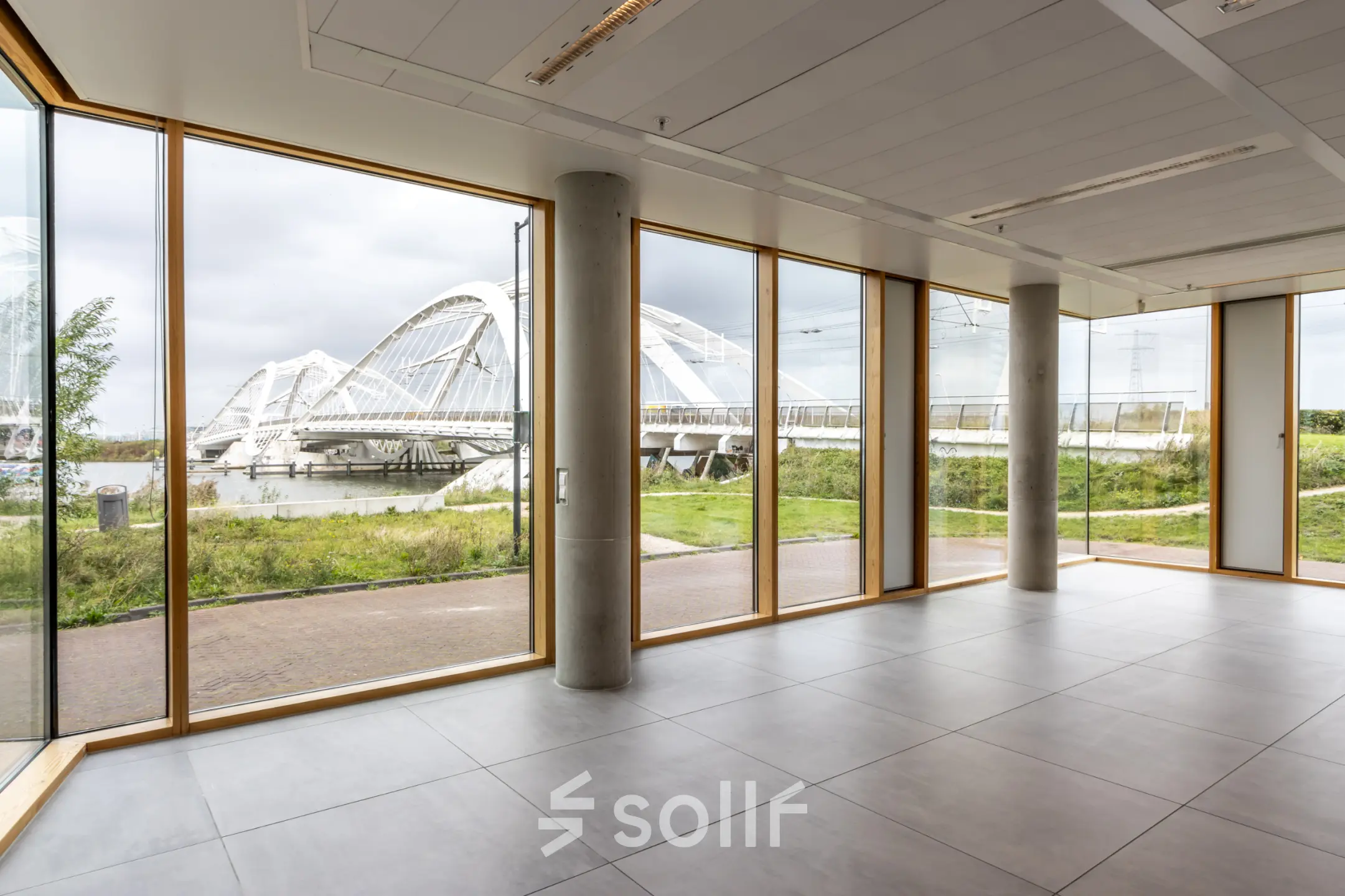Lichte kantoorruimte in Amsterdam IJburg met grote ramen en uitzicht op een brug, ideaal voor wie een kantoor wil huren.