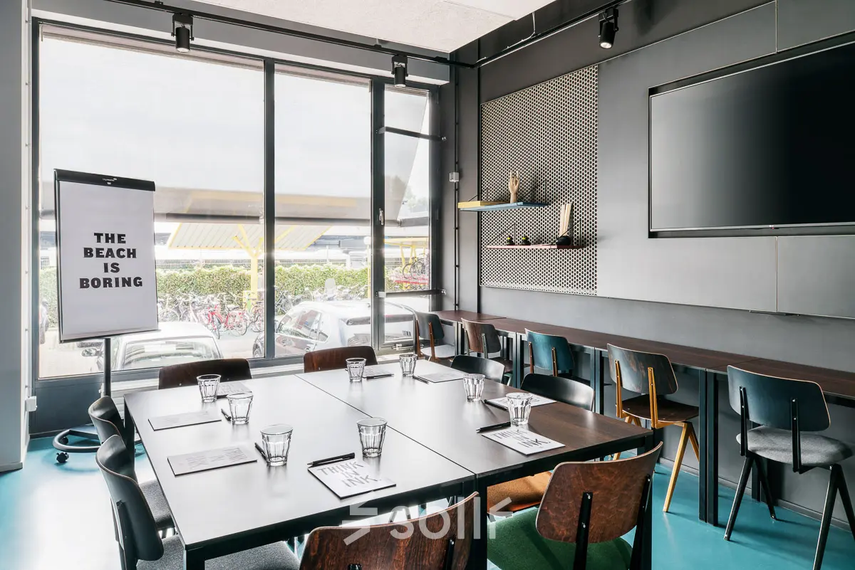 Moderne vergaderruimte met ruime tafels en stoelen in kantoorpand Jan van Galenstraat 335, Amsterdam Nieuw-West. Ideaal voor wie kantoorruimte wil huren met functionele en stijlvolle inrichting.