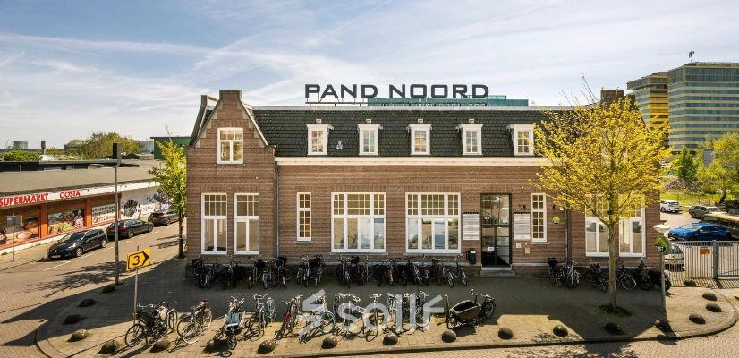 Kantoorgebouw aan de Meeuwenlaan 98-100 in Amsterdam Noord met een bakstenen gevel en fietsenrekken voor de deur. Ideaal voor wie kantoorruimte wil huren in een levendige omgeving.