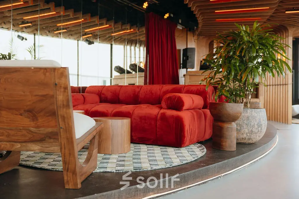 Moderne kantoorruimte met een rode bank en houten elementen op Overhoeksplein 1 in Amsterdam Noord. Ideaal om te huren voor zakelijke bijeenkomsten in een stijlvolle setting.