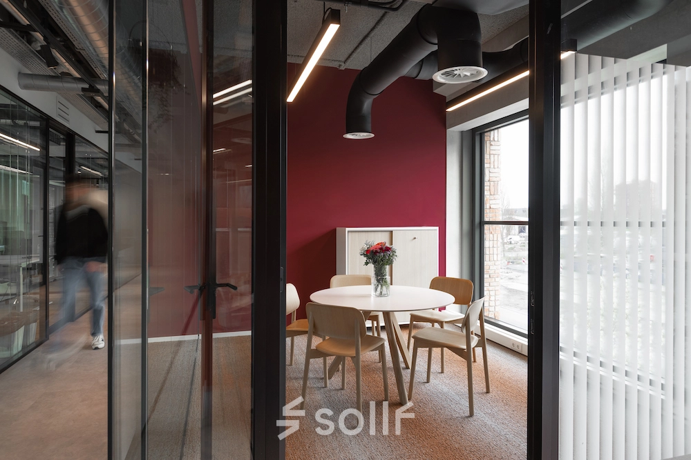 Moderne kantoorruimte op Papaverhof 58 in Amsterdam Noord met een ronde tafel en stoelen, ideaal voor vergaderingen. Grote ramen zorgen voor veel natuurlijk licht.