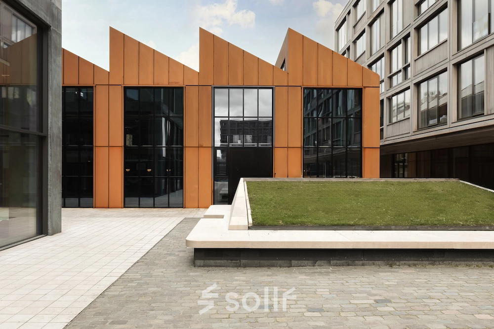 Moderne kantoorpand in Amsterdam Noord met opvallende oranje gevels en groene binnenplaats, ideaal voor kantoorruimte huren.