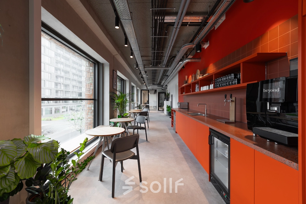 Moderne en stijlvolle pantry op Papaverhof 58 in Amsterdam Noord, ideaal voor bedrijven die kantoorruimte huren zoeken. Voorzien van feloranje elementen en grote ramen met uitzicht.