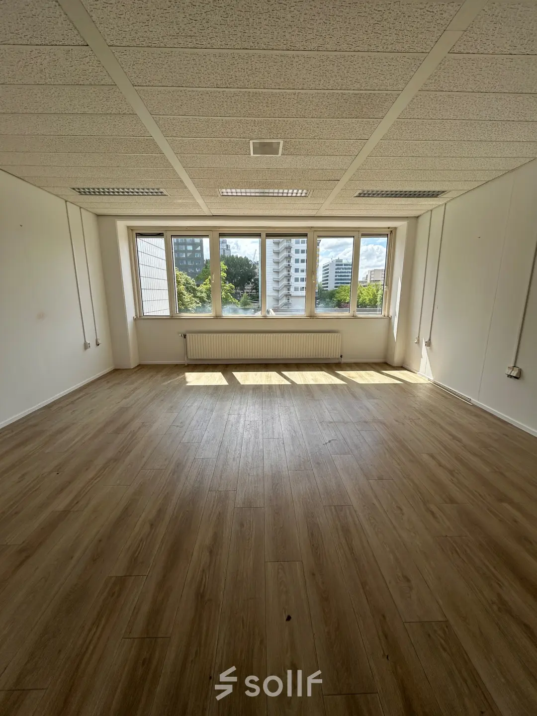 Ongemeubileerde kantoorruimte op James Wattstraat 71, Amsterdam Oost met uitzicht op de stad. Ruimte in een kantoorpand met grote ramen en houten vloer, ideaal om te huren voor een open werkplek.