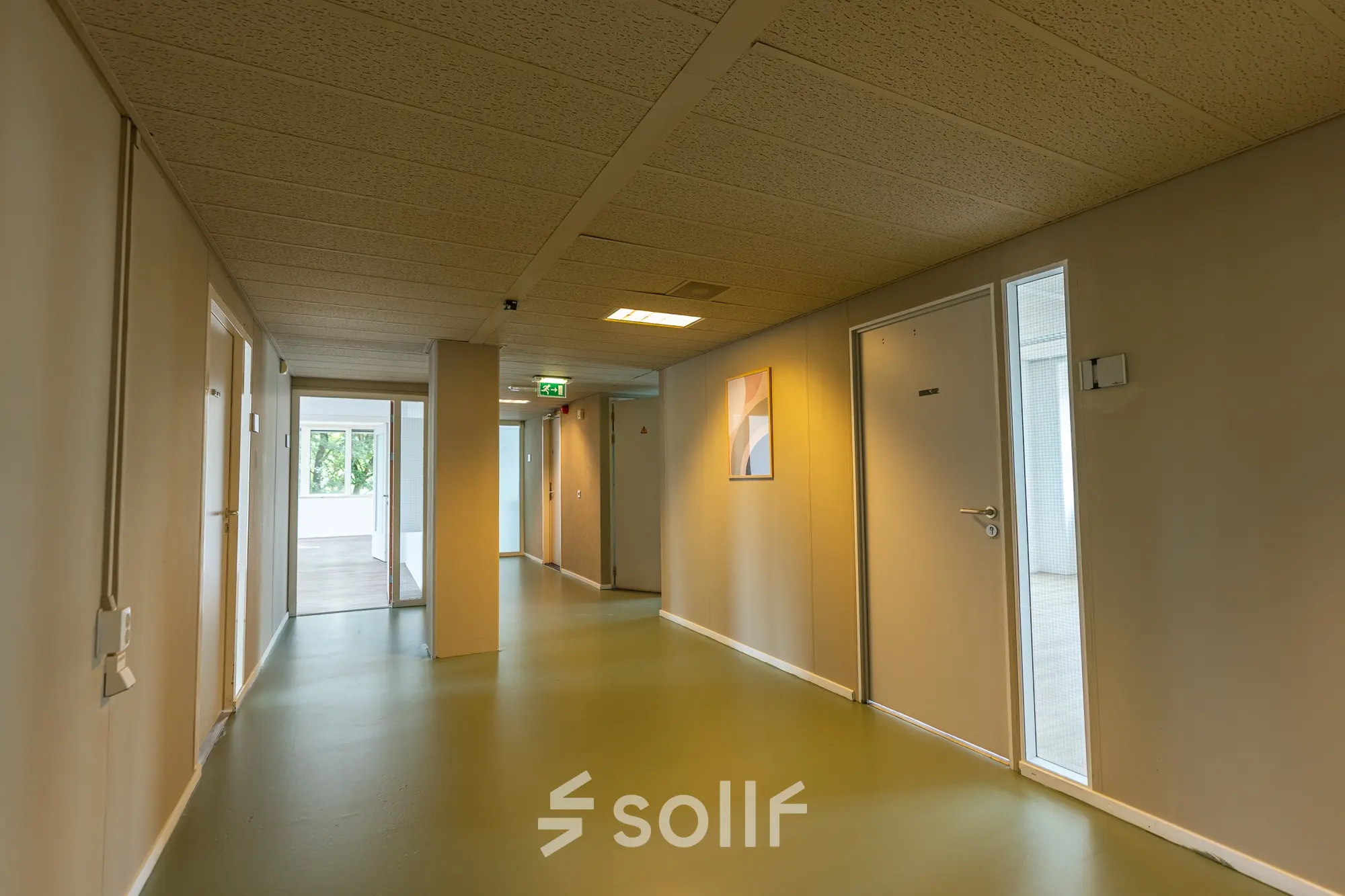 Een moderne gang in een kantoorpand op James Wattstraat 71, Amsterdam Oost, met goed verlichte open deuren die naar verschillende kantoren leiden.
