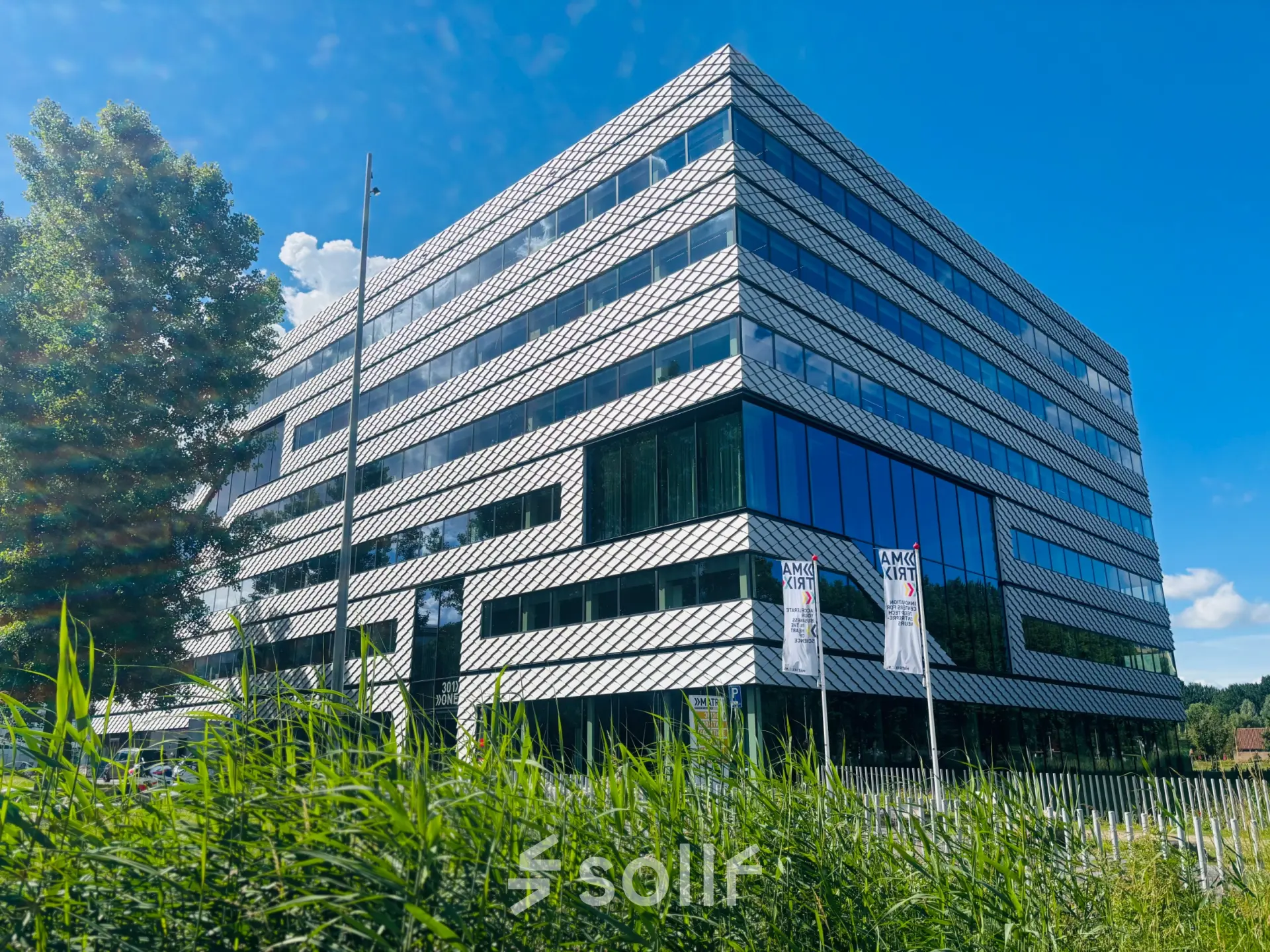 Modern kantoorpand op Science Park 301 in Amsterdam Oost met glas en staal, geschikt voor kantoorruimte huren. Omgeven door groen en een heldere lucht.