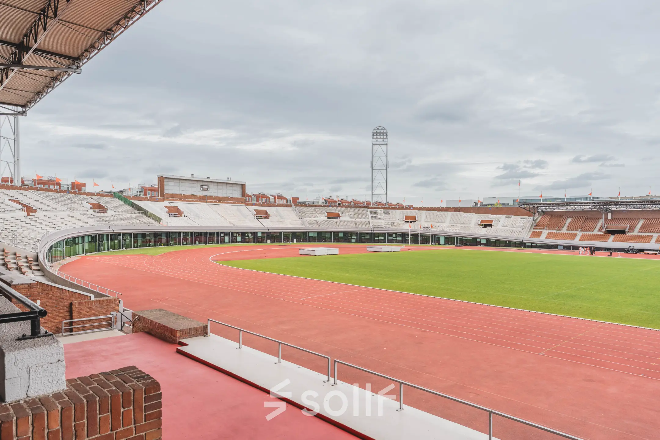 Buitenaanzicht van het Olympisch Stadion in Amsterdam met omringende atletiekbaan, ideaal als locatie voor evenementen of kantoorruimte huren.