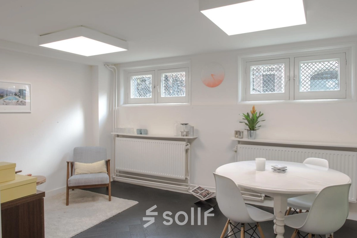 Kantoorruimte huren aan de Sophialaan 21 in Amsterdam Oud Zuid met een gemeubileerde loungehoek inclusief fauteuil en eettafel. Witte muren en vloerkleed zorgen voor een lichte en uitnodigende sfeer.