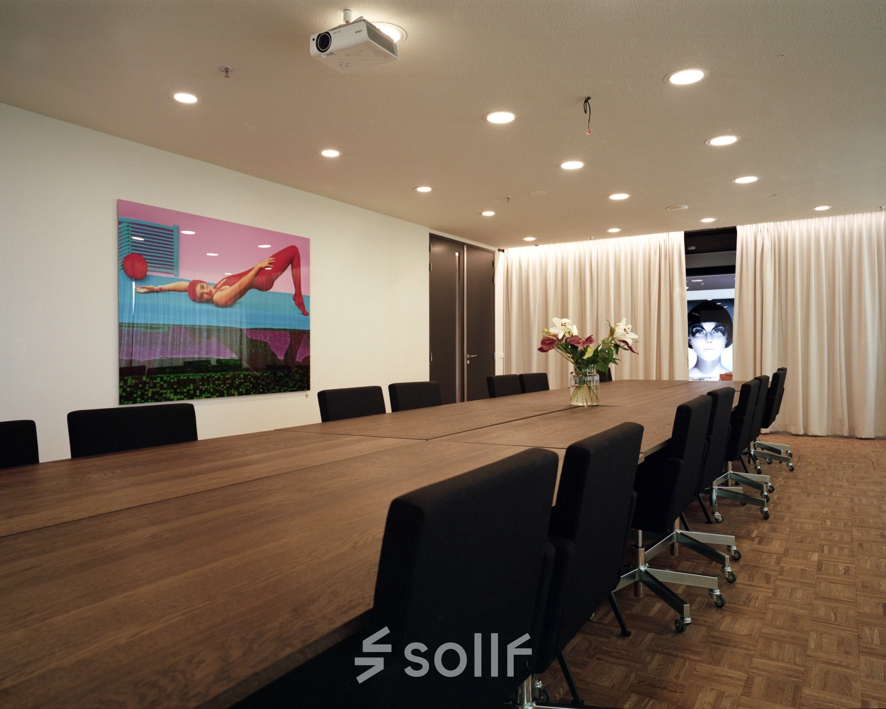 Moderne vergaderruimte in kantoorpand op Johan Huizingalaan 400, Amsterdam Riekerpolder met lange houten tafel, comfortabele stoelen en creatieve kunst aan de muur. Ideaal voor het huren van een inspirerende werkplek.