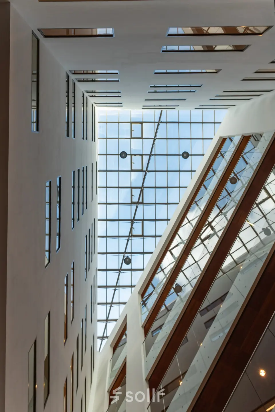 Binnenaanzicht van een modern kantoorpand op John M. Keynesplein in Amsterdam Riekerpolder, met grote glazen plafonds en verzonken verlichting. Ideaal voor kantoorruimte huren in een inspirerende omgeving.