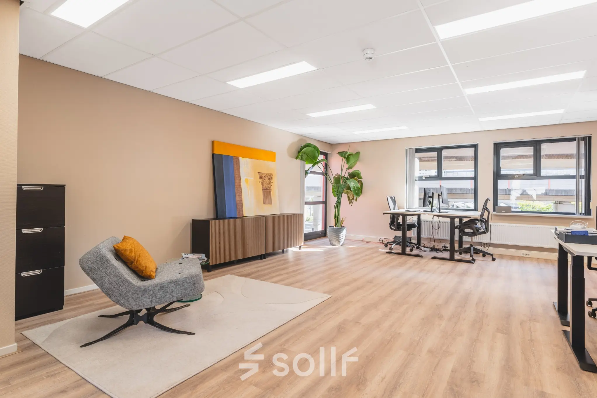 Ruime kantoorruimte huren in Amsterdam Sloterdijk aan Arlandaweg 92 met moderne meubels, bureaus en een grote plant, geschikt voor werk en vergaderingen.