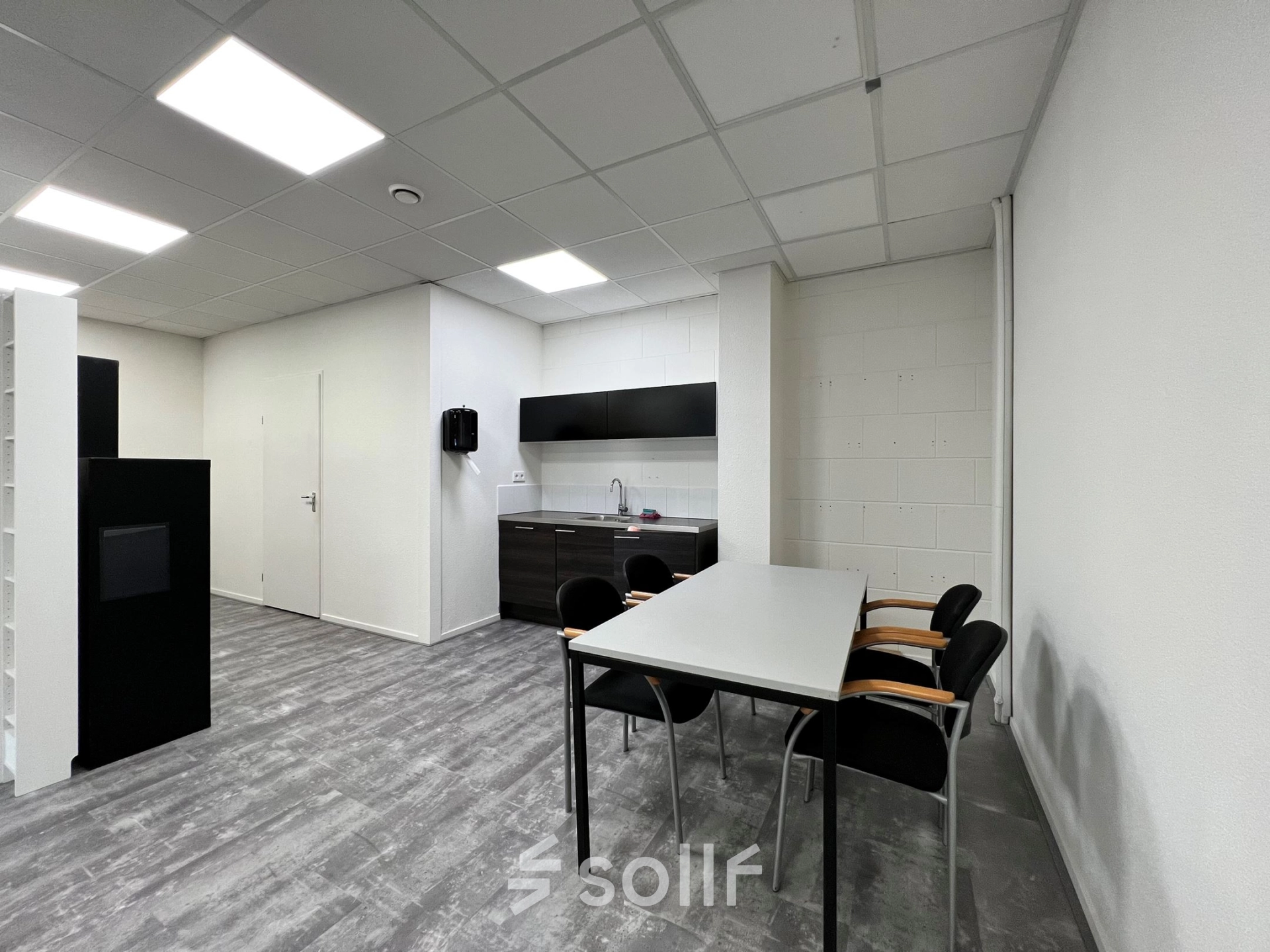 Moderne kantoorruimte huren aan de Contactweg 131 in Amsterdam Sloterdijk, met strakke vloeren, witte muren en een kitchenette met stoelen, ideaal voor diverse zakelijke activiteiten.
