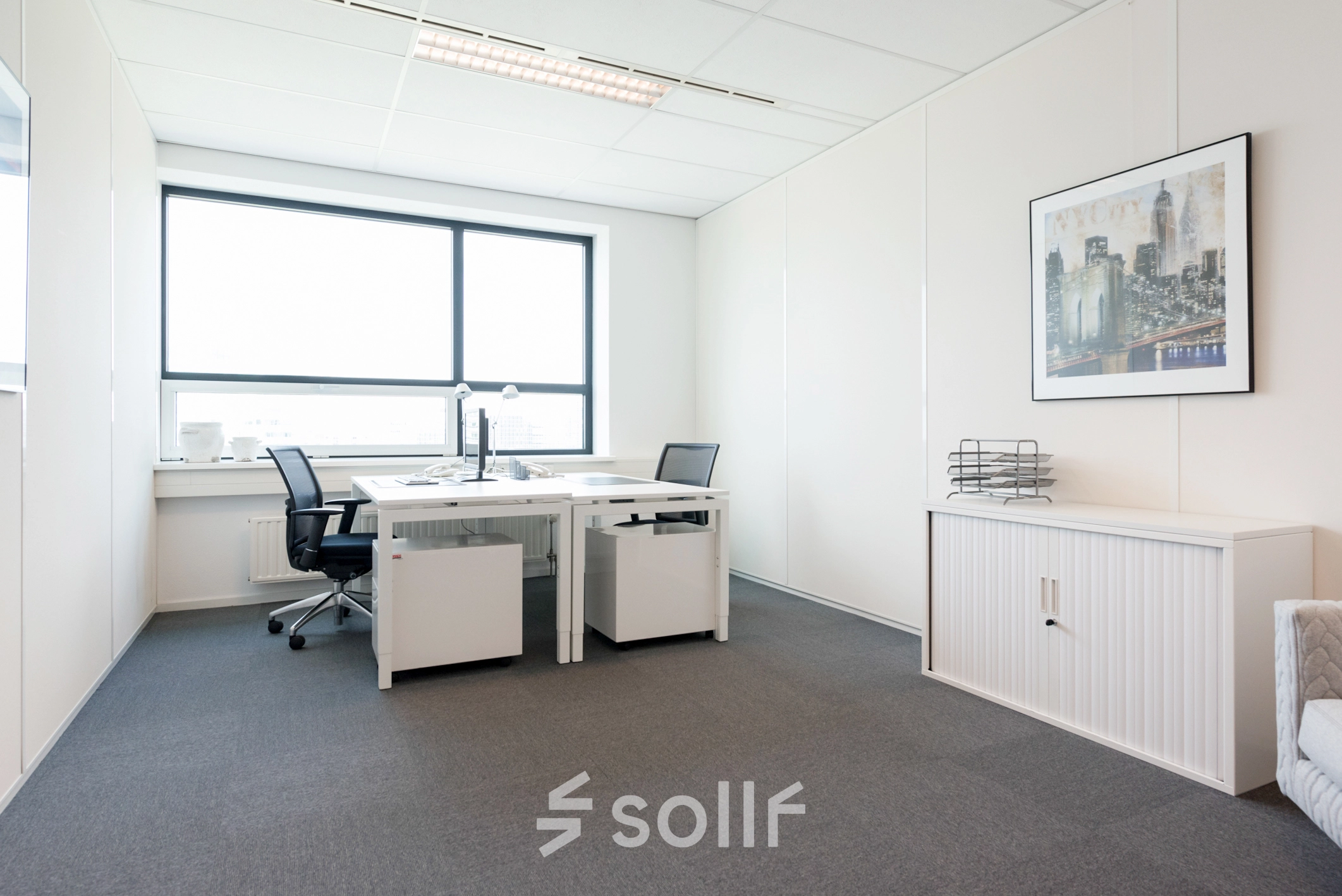 Goed verlichte kantoorruimte huren aan Teleportboulevard 110 in Amsterdam Sloterdijk met strak interieur, twee bureaus en een grote raam. Ideaal voor een productieve werksfeer in een kantoorpand.
