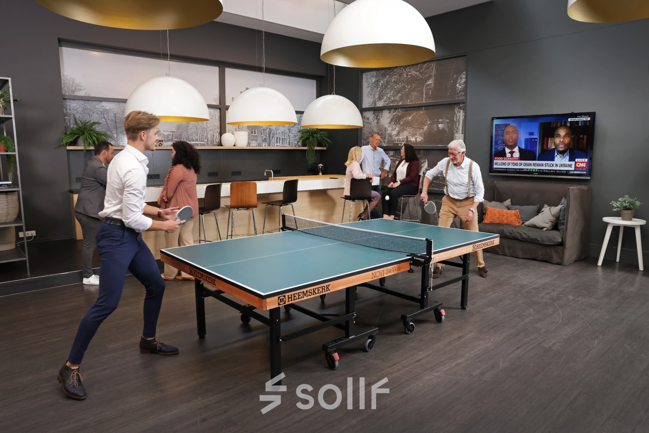 Grote kantoorruimte in Amsterdam Sloterdijk met mensen die tafeltennis spelen en anderen die bij de bar zitten en netwerken. Gezellige sfeer geschikt voor huur als creatieve werkruimte.