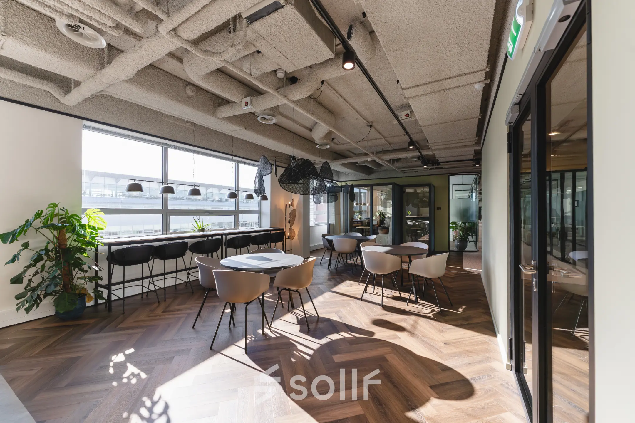 Moderne kantoorruimte huren met uitzicht op Bos en Lommerplein in Amsterdam West. Het kantoorpand heeft een open indeling, grote ramen, houten vloer en stijlvolle meubels.