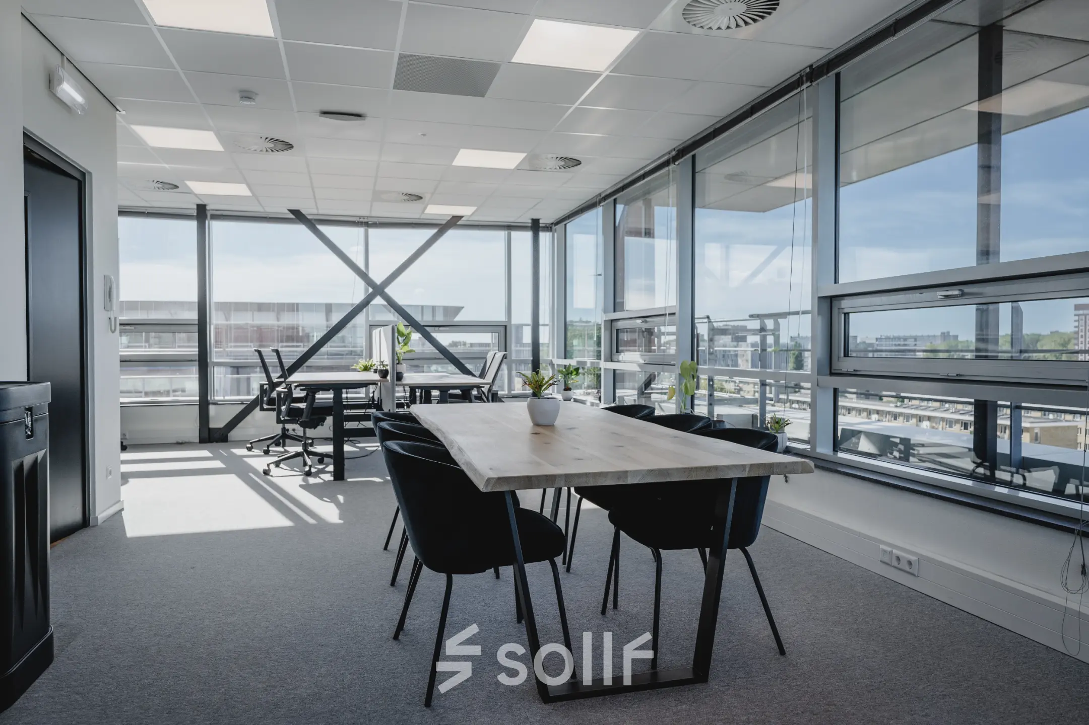 Moderne kantoorruimte te huur in Amsterdam West met grote ramen voor natuurlijk licht, voorzien van tafel en stoelen voor vergaderingen.