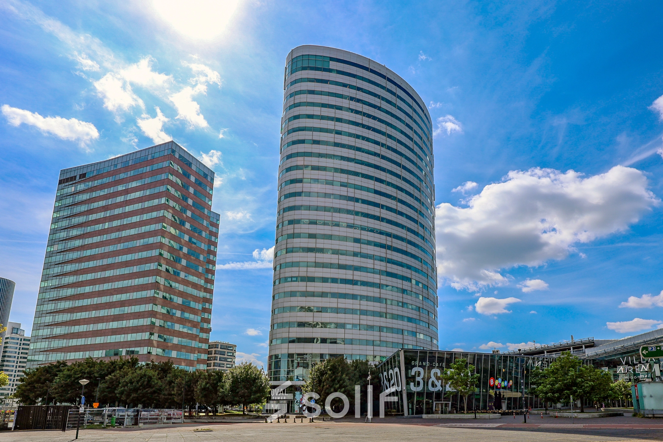 Modern kantoorpand op De Entree 99-197 in Amsterdam Zuid-Oost met indrukwekkende gevel en glaswerk. Ideaal voor kantoorruimte huren. Blauw lucht complimenteert het ontwerp van de moderne kantoren.