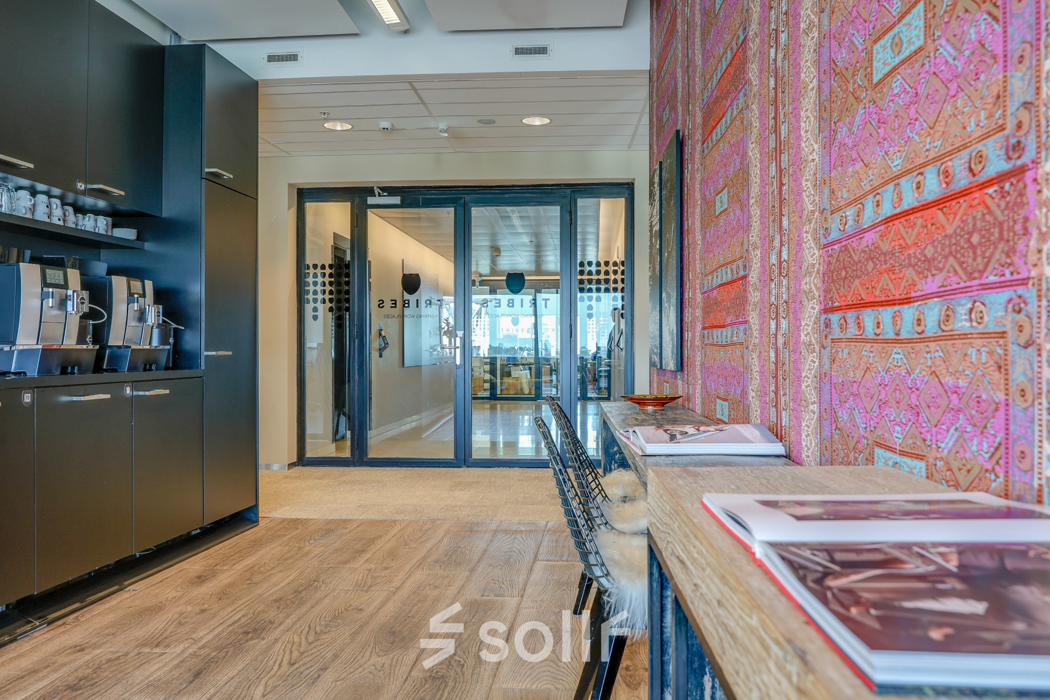 Kantoorpand in Amsterdam Zuid-Oost met kleurrijke wandbekleding en moderne koffiehoek. Perfect voor kantoorruimte huren. De stijl is eigentijds en uitnodigend, ideaal voor een professionele werkruimte.