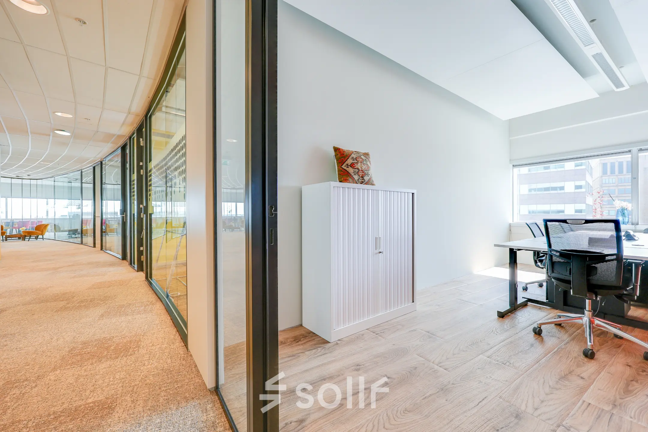 Moderne kantoorruimte met glazen wanden en houten vloer aan De Entree 99-197 in Amsterdam Zuid-Oost, ingericht met bureau en kast, beschikbaar voor kantoorruimte huren.