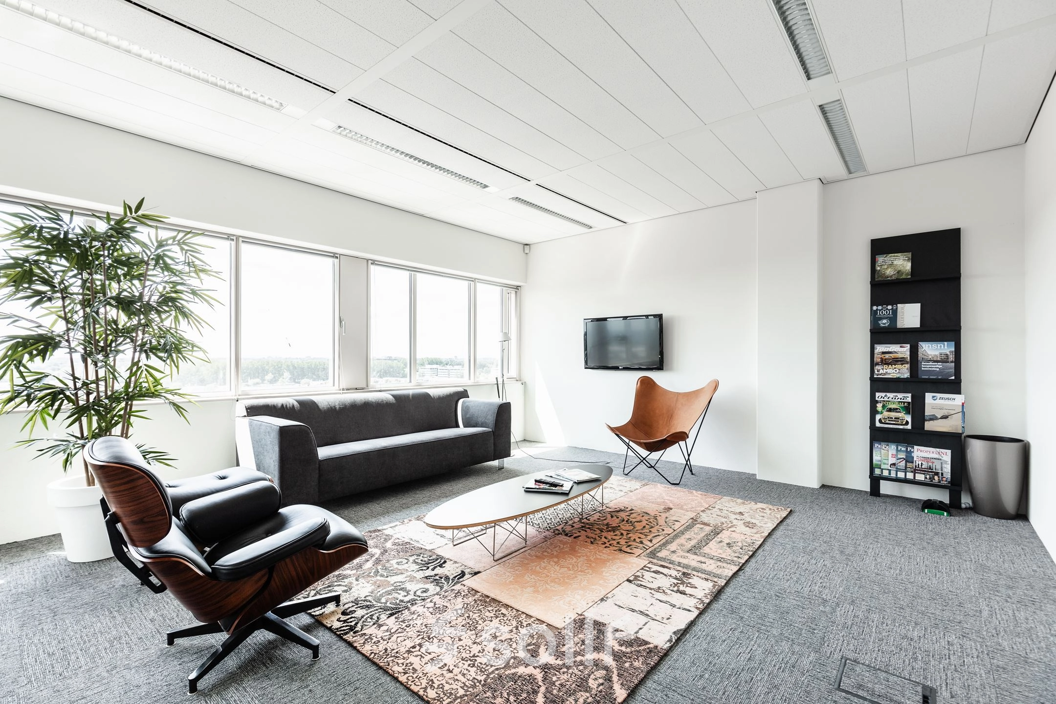 Lichte kantoorruimte met zitgedeelte inclusief sofa, fauteuils en een tapijt, ideaal om te huren op Herikerbergweg 240-286 in Amsterdam Zuid-Oost.