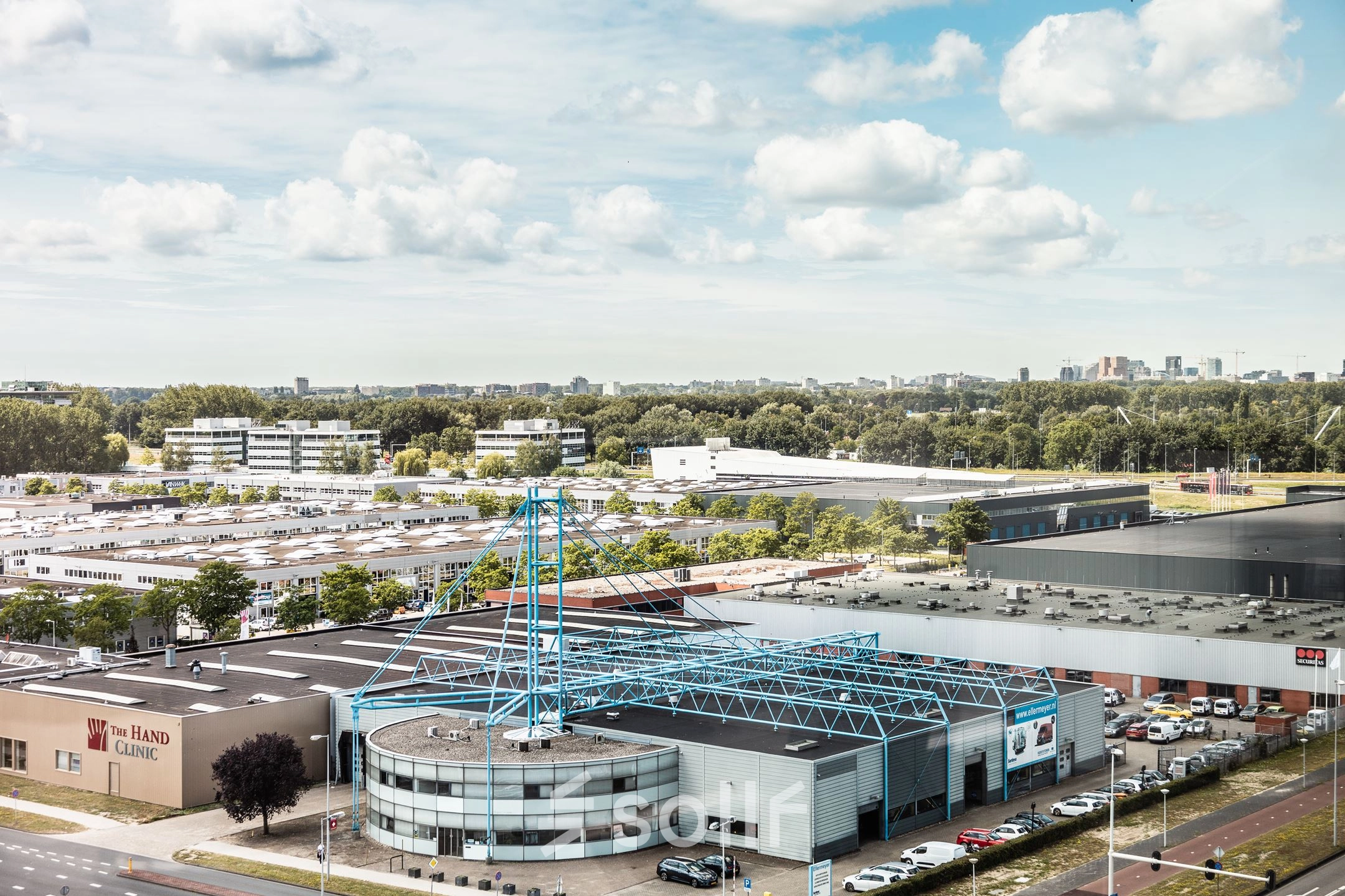 Luchtfoto van een kantoorpand aan de Herikerbergweg 240-286 in Amsterdam Zuid-Oost, omgeven door andere bedrijfsgebouwen en een groene omgeving.