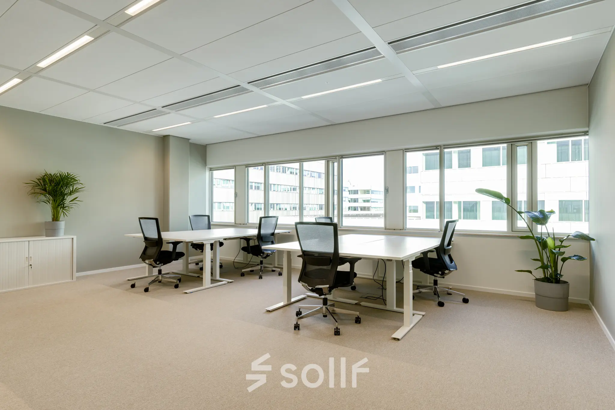 Heldere kantoorruimte te huur op Herikerbergweg 288 in Amsterdam Zuid-Oost, met grote ramen, vier bureaus en comfortabele stoelen.