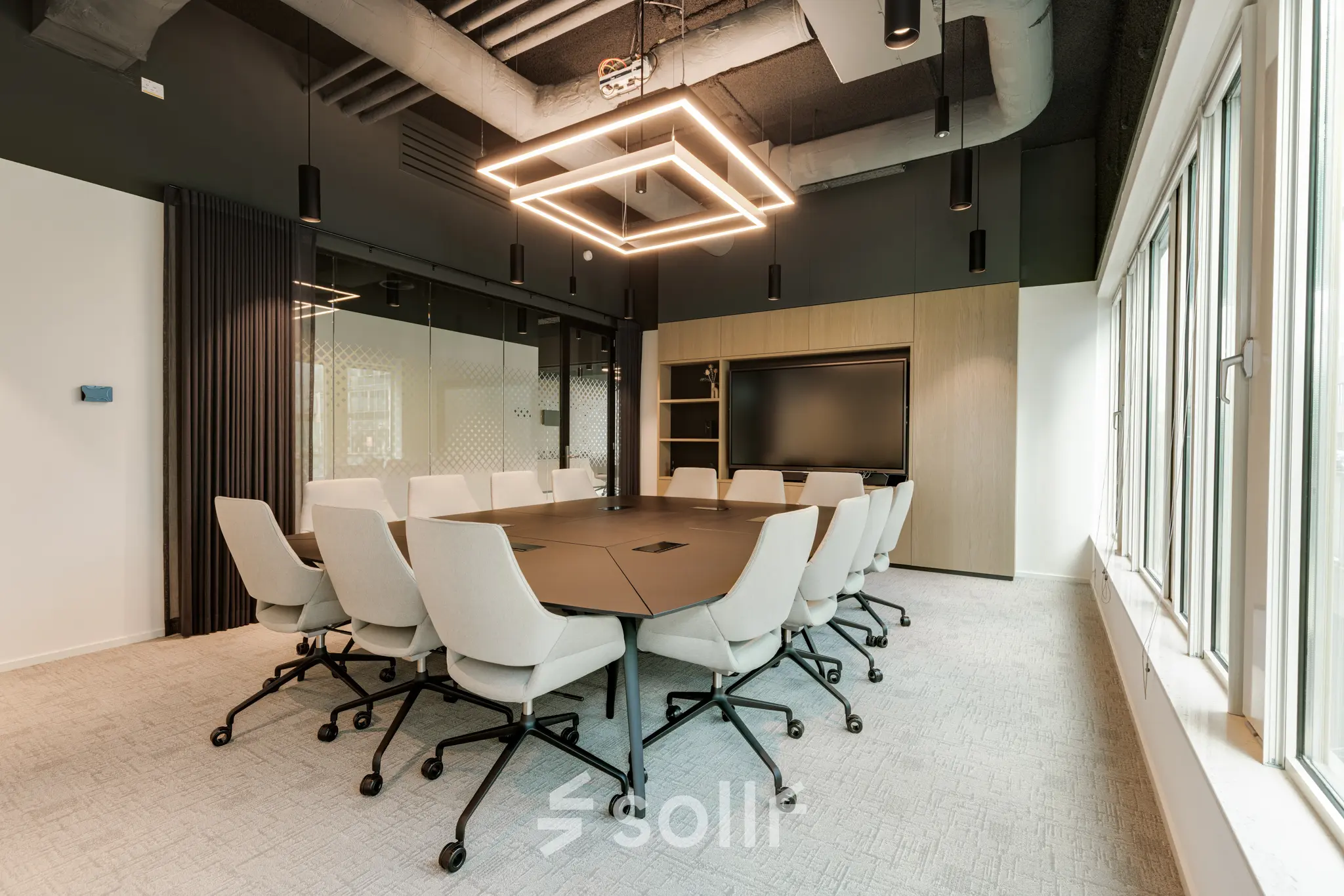 Moderne vergaderruimte in kantoorpand op Herikerbergweg 288, Amsterdam Zuid-Oost. Comfortabele stoelen rond een grote tafel, ideaal voor zakelijke bijeenkomsten. Grote ramen zorgen voor veel natuurlijk licht.