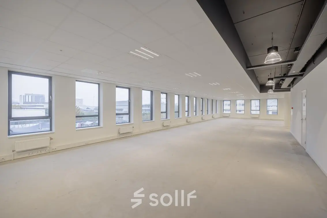 Ruime kantoorruimte te huur op Hogehilweg 24 in Amsterdam Zuid-Oost, met veel natuurlijk licht door grote ramen en een modern plafondontwerp.