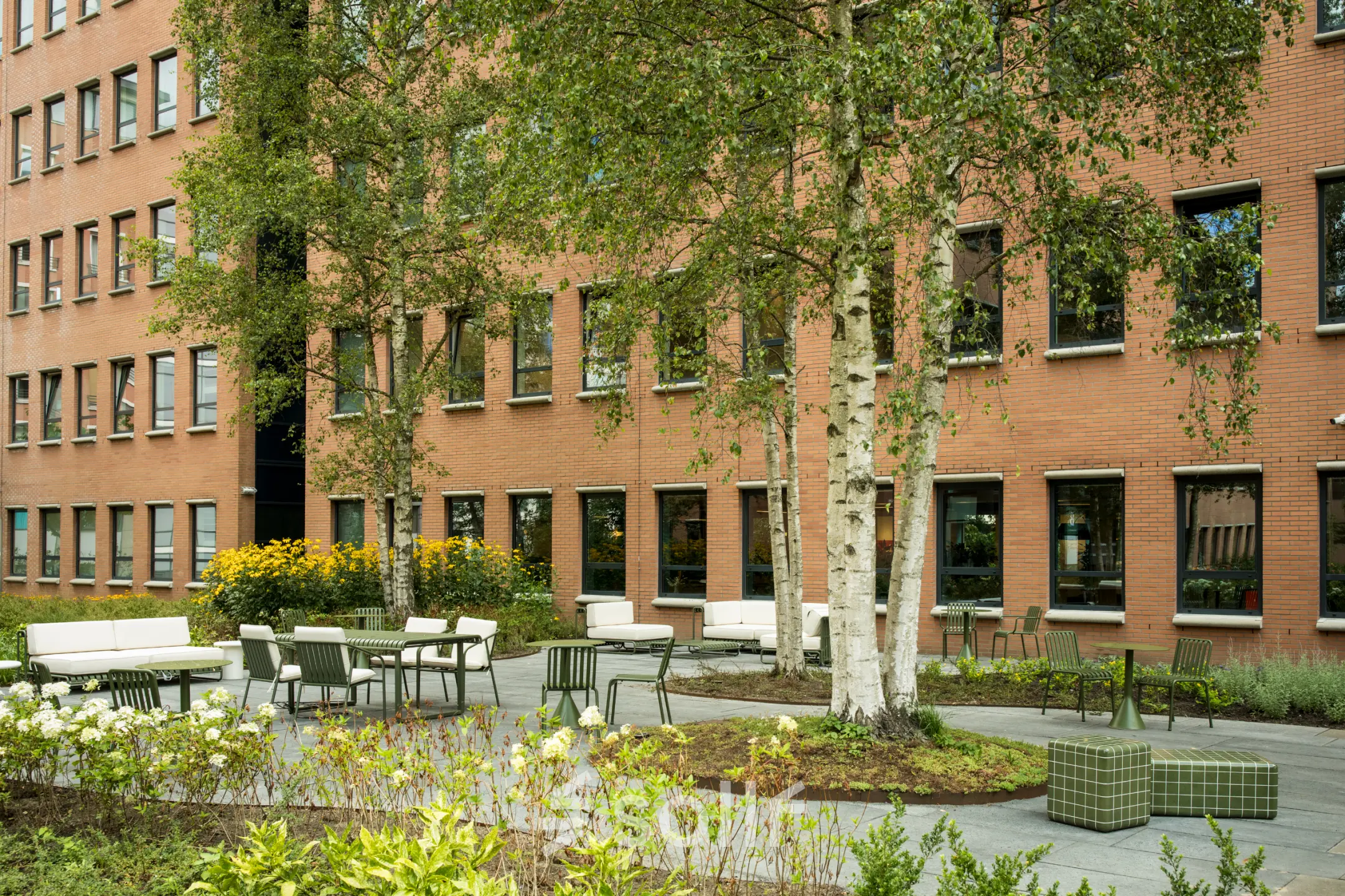 Buitenkantooromgeving met groene planten, tafels en stoelen bij Hullenbergweg 109-135, Amsterdam Zuid-Oost, ideaal voor kantoorruimte huren.