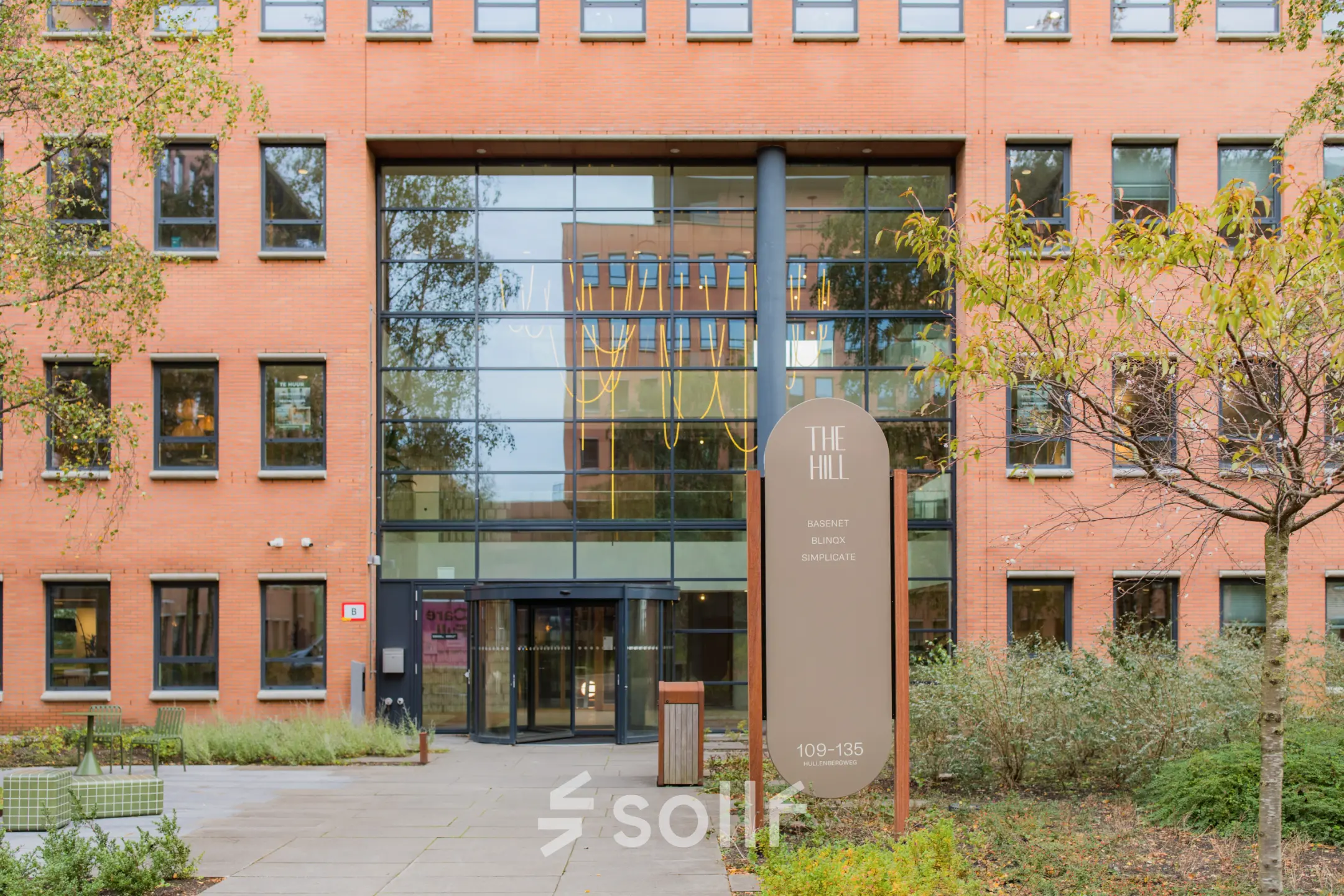 Buitenzijde van kantoorpand op Hullenbergweg 109-135, Amsterdam Zuid-Oost, met glazen entree, omgeven door groen.